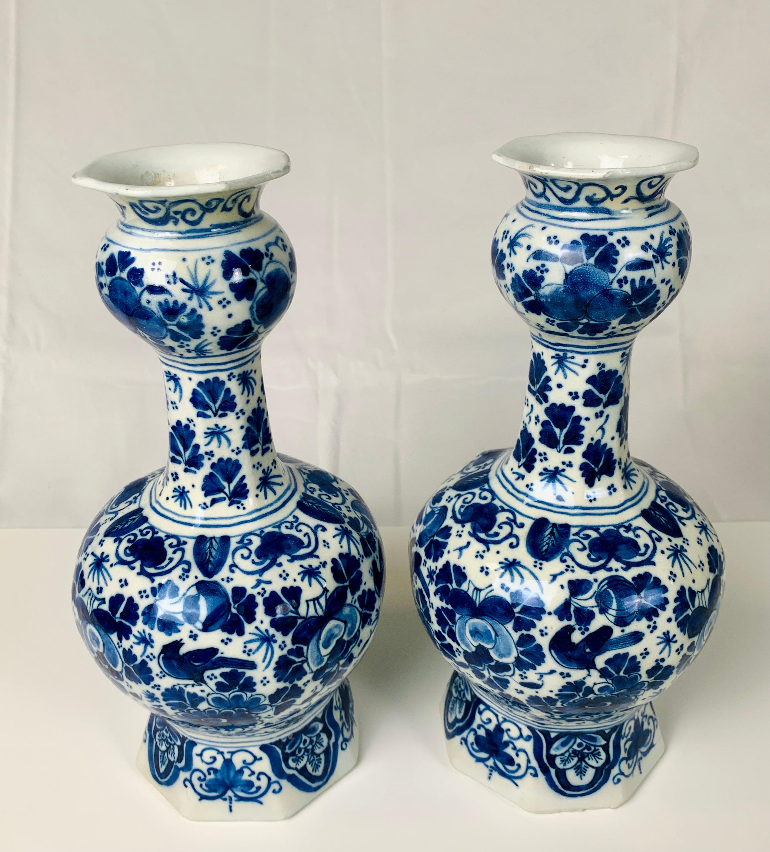 This pair of blue and white Dutch Delft vases was hand-painted in cobalt blue. 
The exquisite blue decoration features an all-around scene in the 