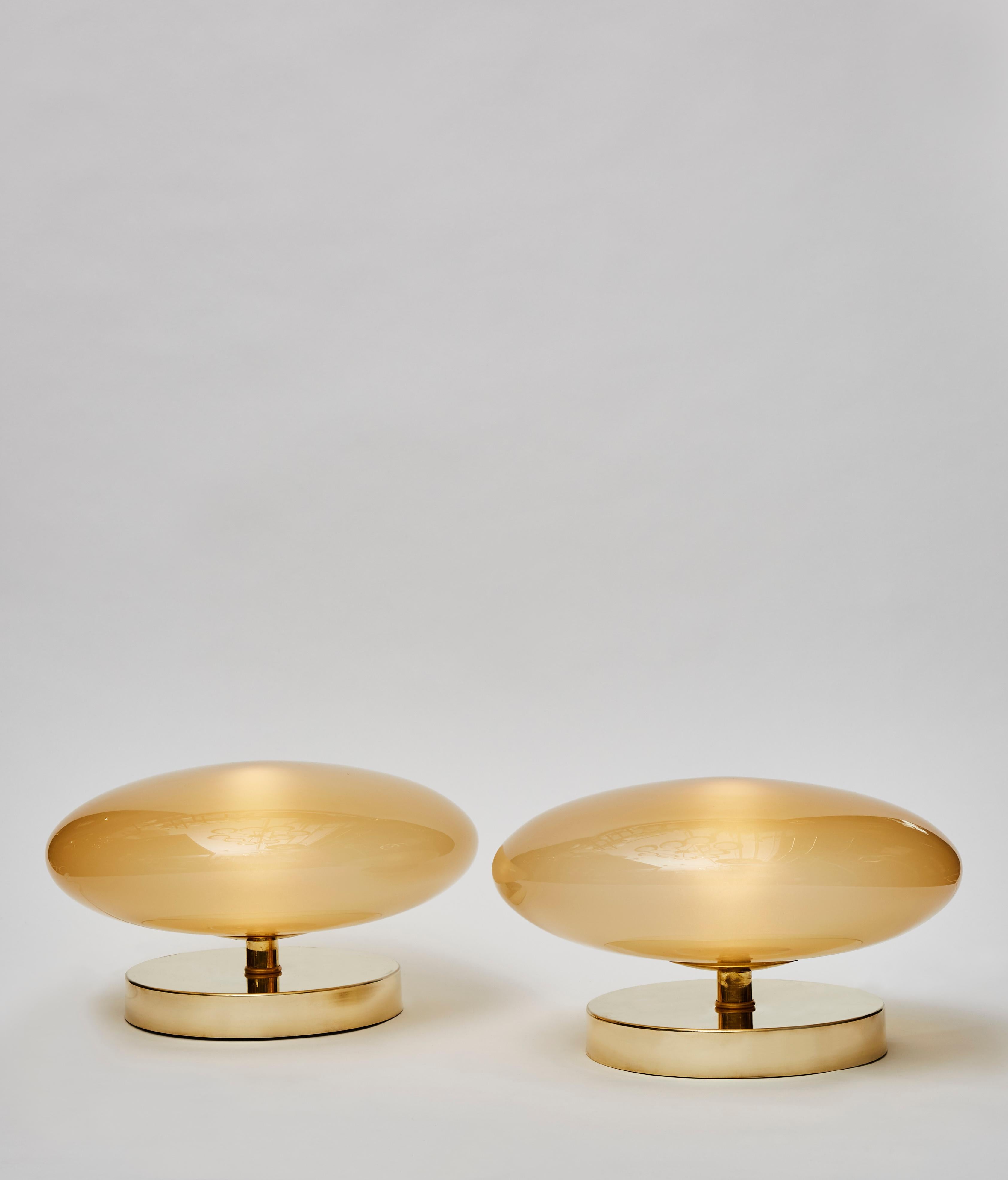 Pair of small table lamps, made of brass feet and wide tinted glass globe.