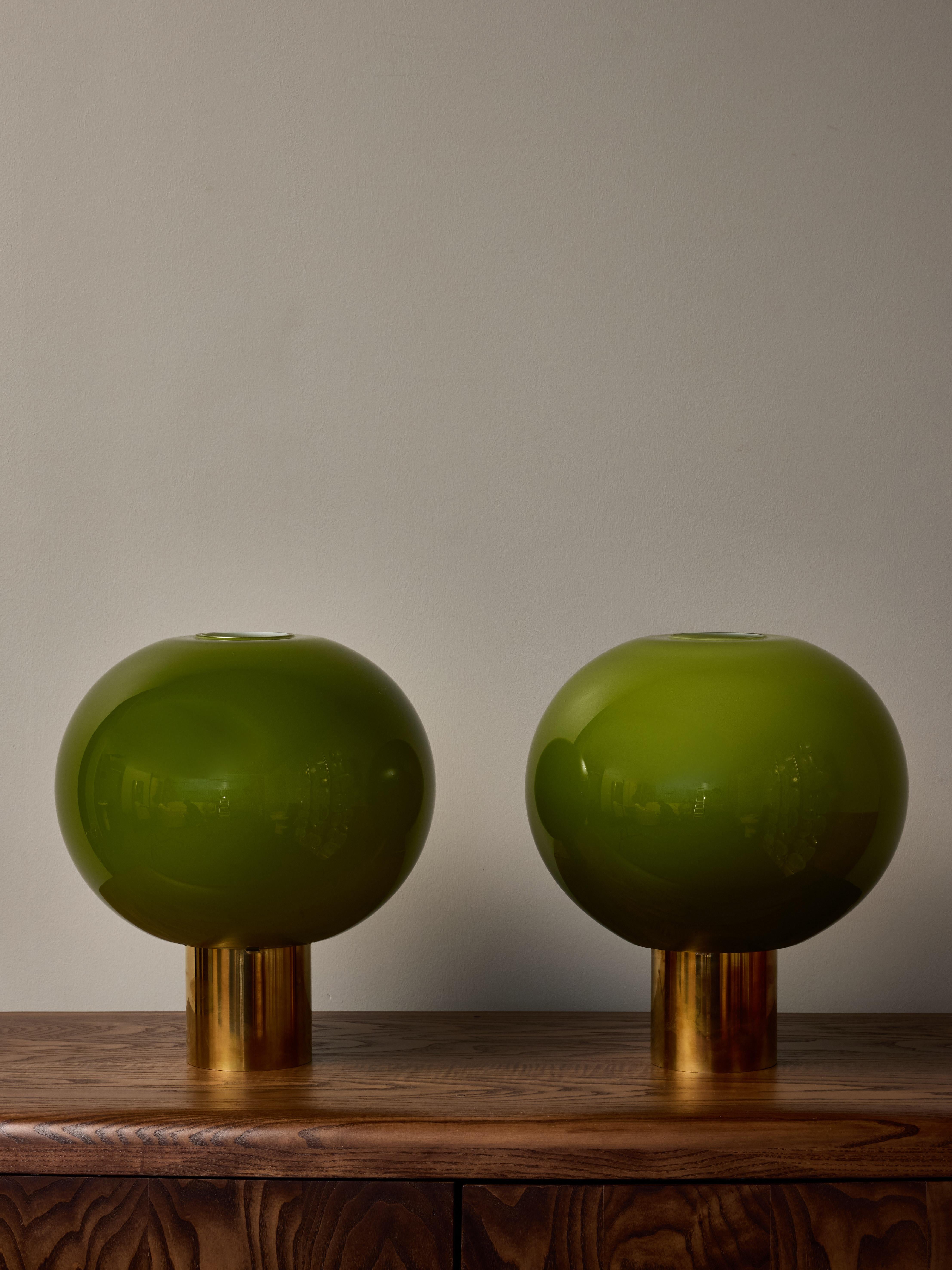 Pair of small table lamps, made of a brass cylinder foot topped with an opened top glass globe tinted in a matcha colour. Ideal for a bedside use thanks to their small size and dimmed light.