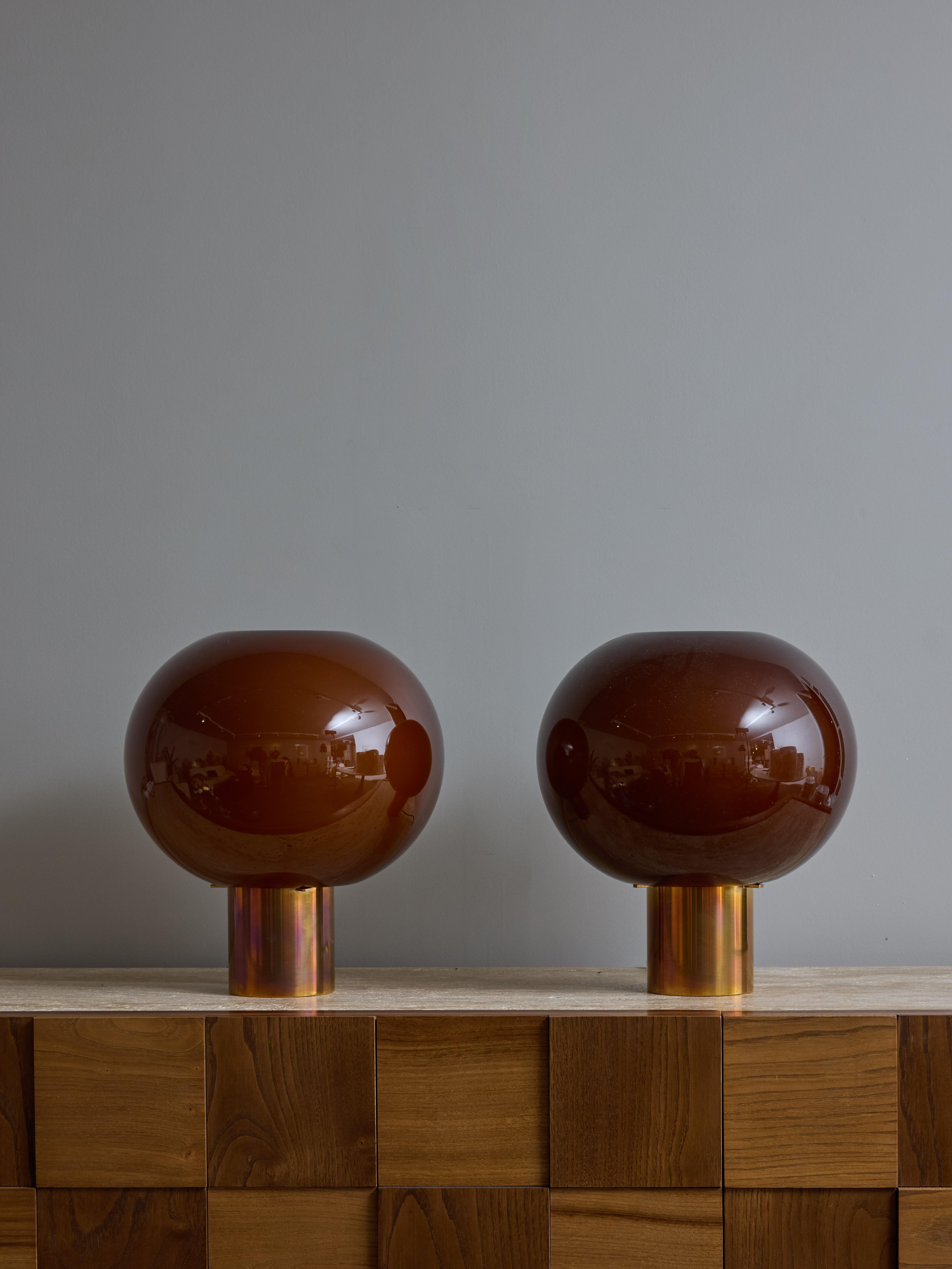 Paire de petites lampes de table, composées d'un pied cylindrique en laiton surmonté d'un globe en verre ouvert teinté dans une couleur tabac. Idéales pour une utilisation de chevet grâce à leur petite taille et à leur lumière tamisée.