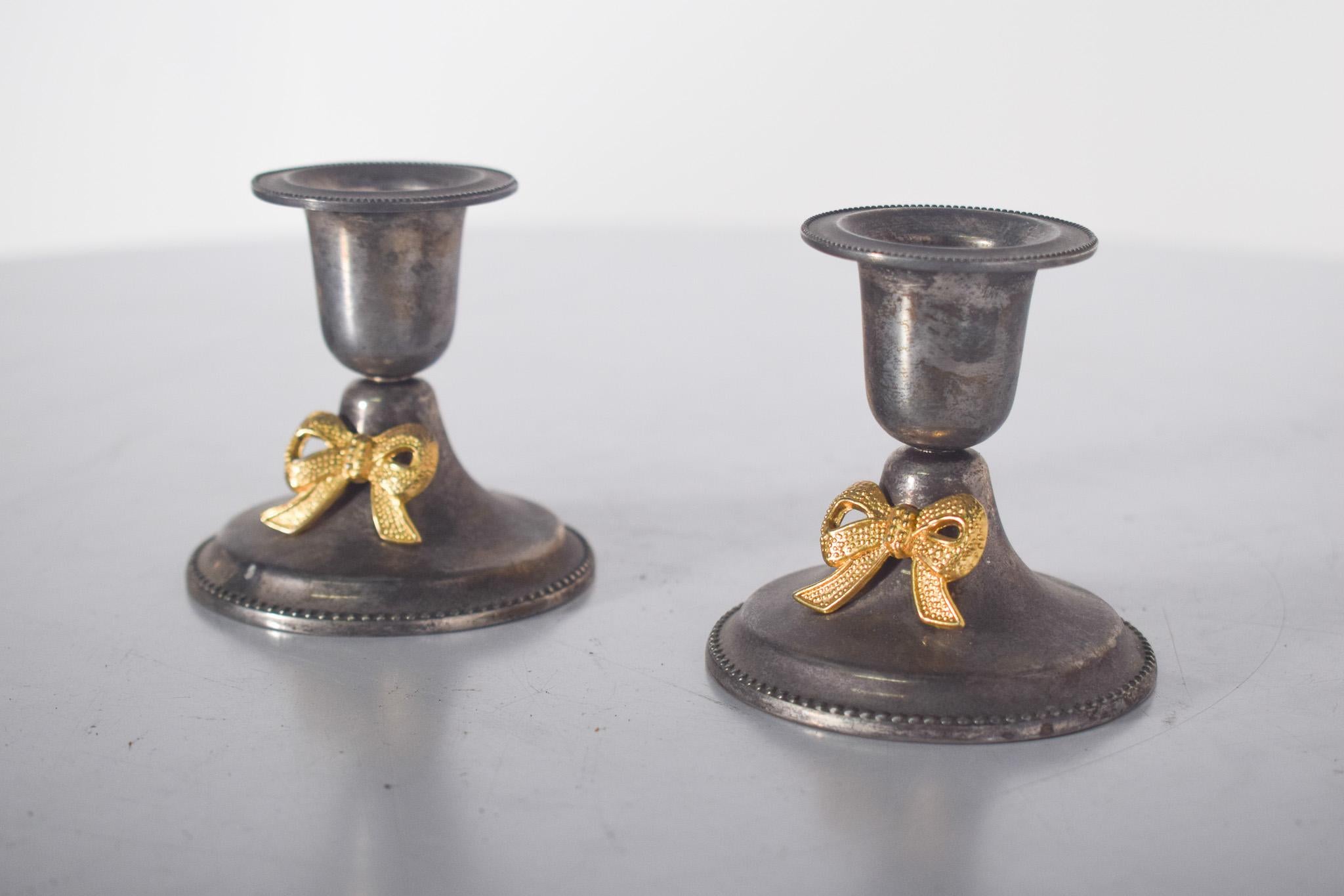 Paire de petits chandeliers en métal argenté. Doté de deux corps et d'une base ronde nacrée, il est surmonté d'un bougeoir en forme de coupe.
La tige courte et légèrement étroite se déploie en un support en forme de bol conçu pour accueillir des