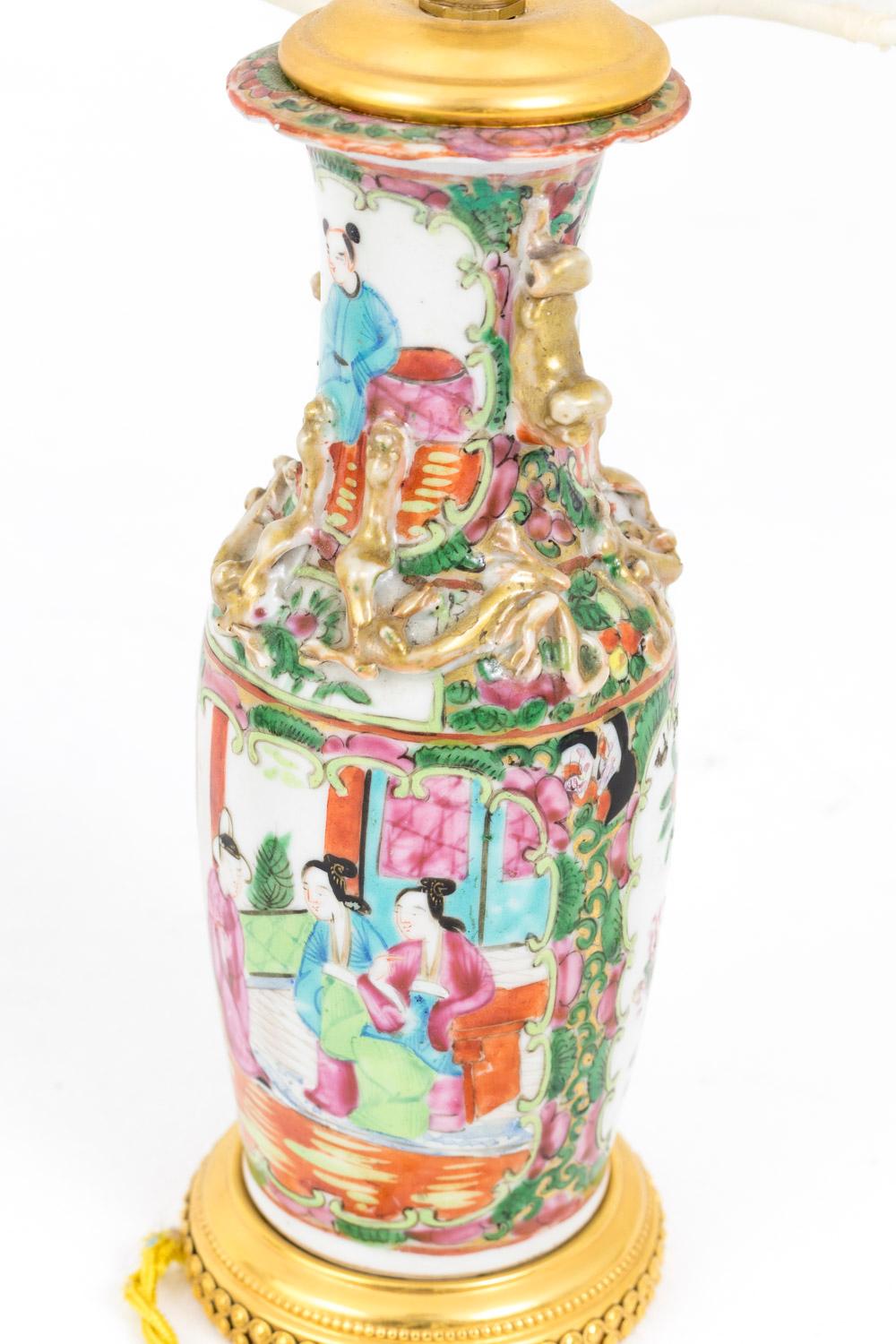 Pair of small bottle shape Canton porcelain lamps with a decor figuring palace scenes in cartouches on one side and flowers and birds on the other side, both framed by flowers and foliage. On the neck, ornamentation of sat Asian characters in
