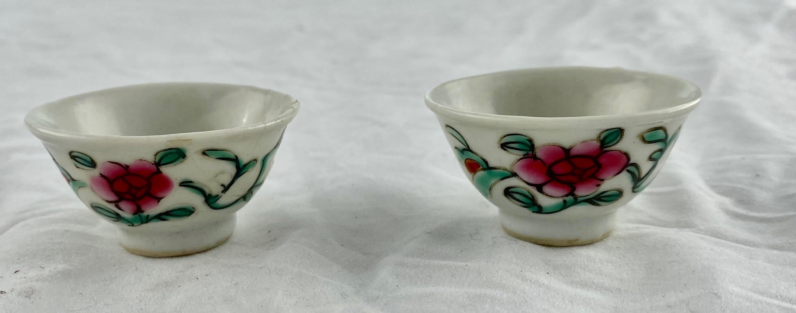A pair of small porcelain cups decorated in famille rose colours, early 19th c. One of the cups severely damaged/repaired.