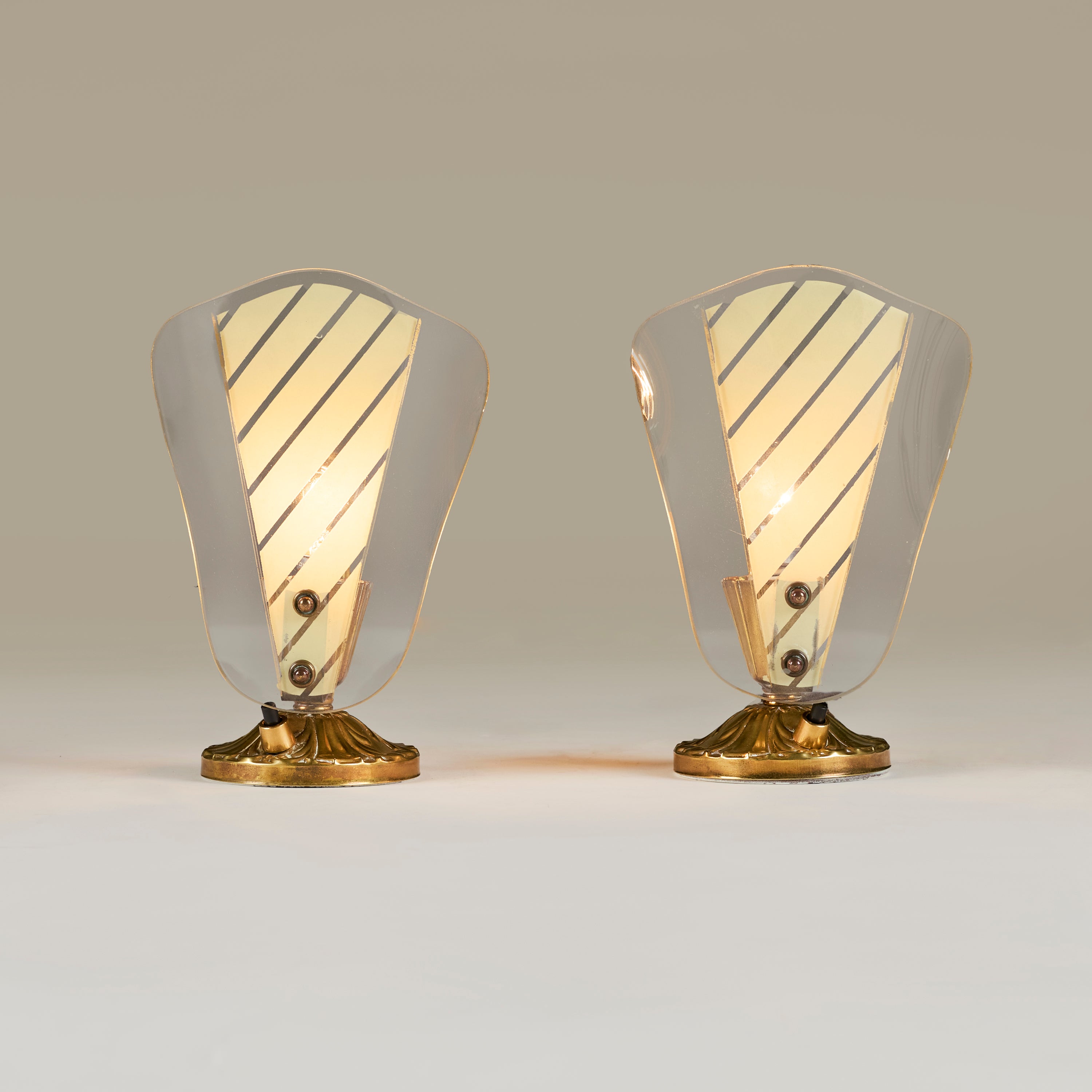 Paire inhabituelle de petites lampes de coiffeuse/de table. Ferrure décorative en laiton en forme de bâton de chambre, chacune avec un panneau de verre rayé fixé par deux attaches en laiton. L'interrupteur marche/arrêt se trouve sur une base