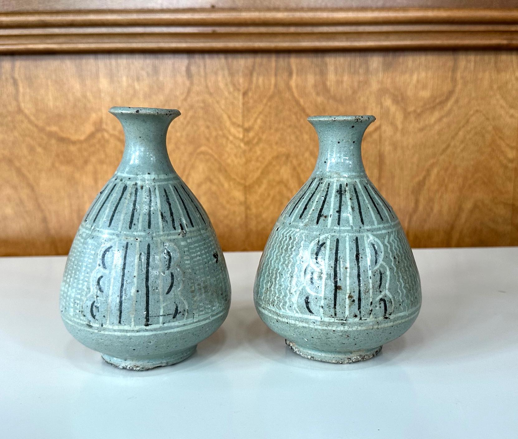 Angeboten wird eine fast paarige antike koreanische Keramikvase vom Ende der Goryeo bis zum Beginn der Joseon-Periode (ca. 14-15.). Die Vasen haben eine keladonfarbene Craquelé-Glasur mit Unterglasur-Intarsien in Schwarz und Weiß. Diese Art von Vase
