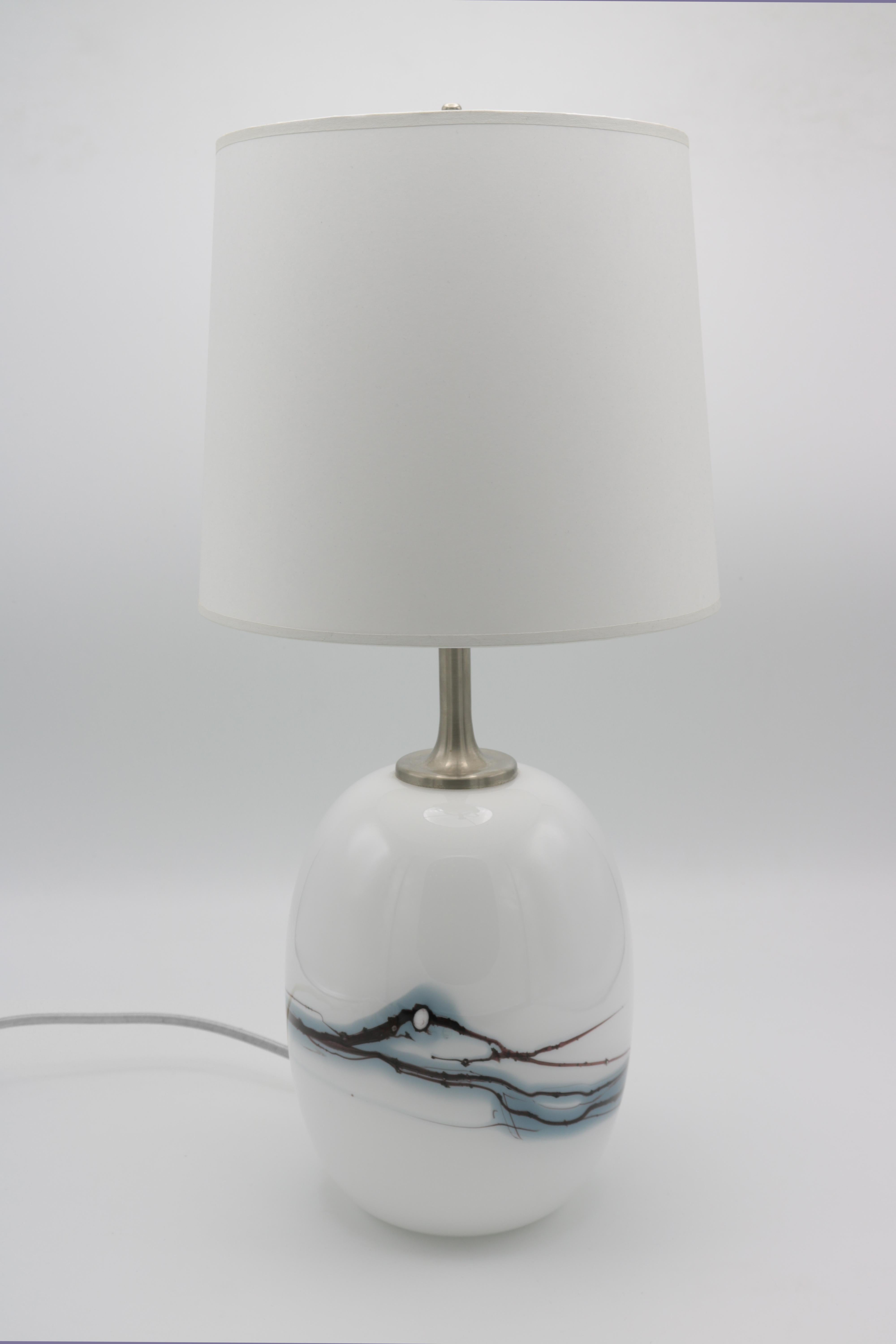 A pair of small Michael Bang designed for Holmegaard Modernist Table Lamps. 
White cased glass with abstract blue swirl details and nickel fittings.