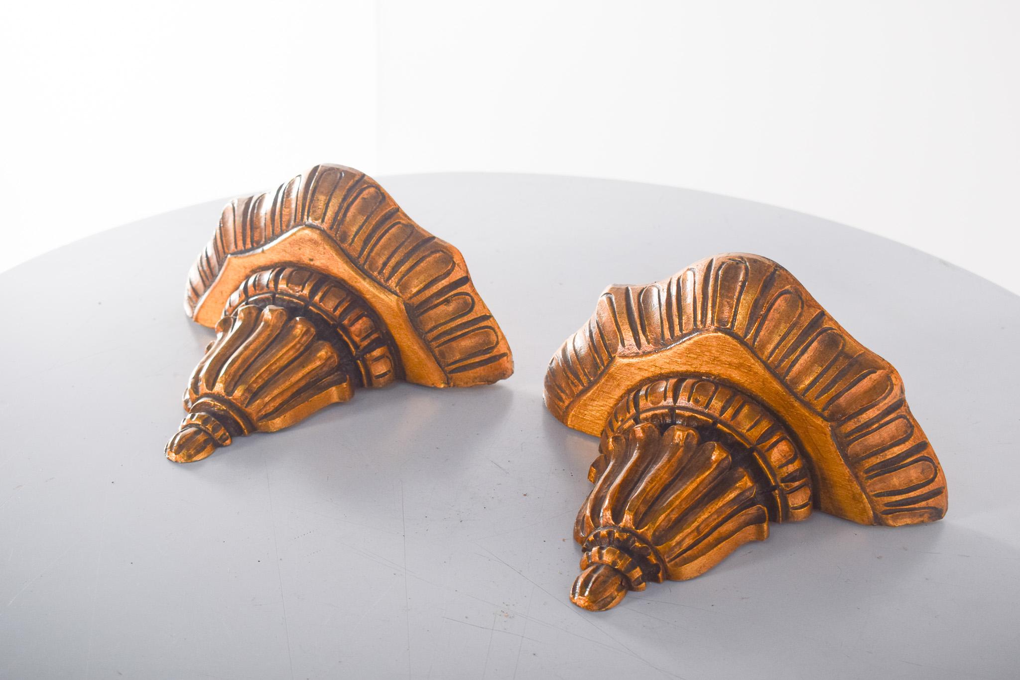 Pair of small pedestals in gilded wood. Decorated in gold and shaped in a baroque style. The pieces feature scrolls and carved elements in relief, reminiscent of traditional French motifs from the 1940s. The gold adds a touch of refinement,