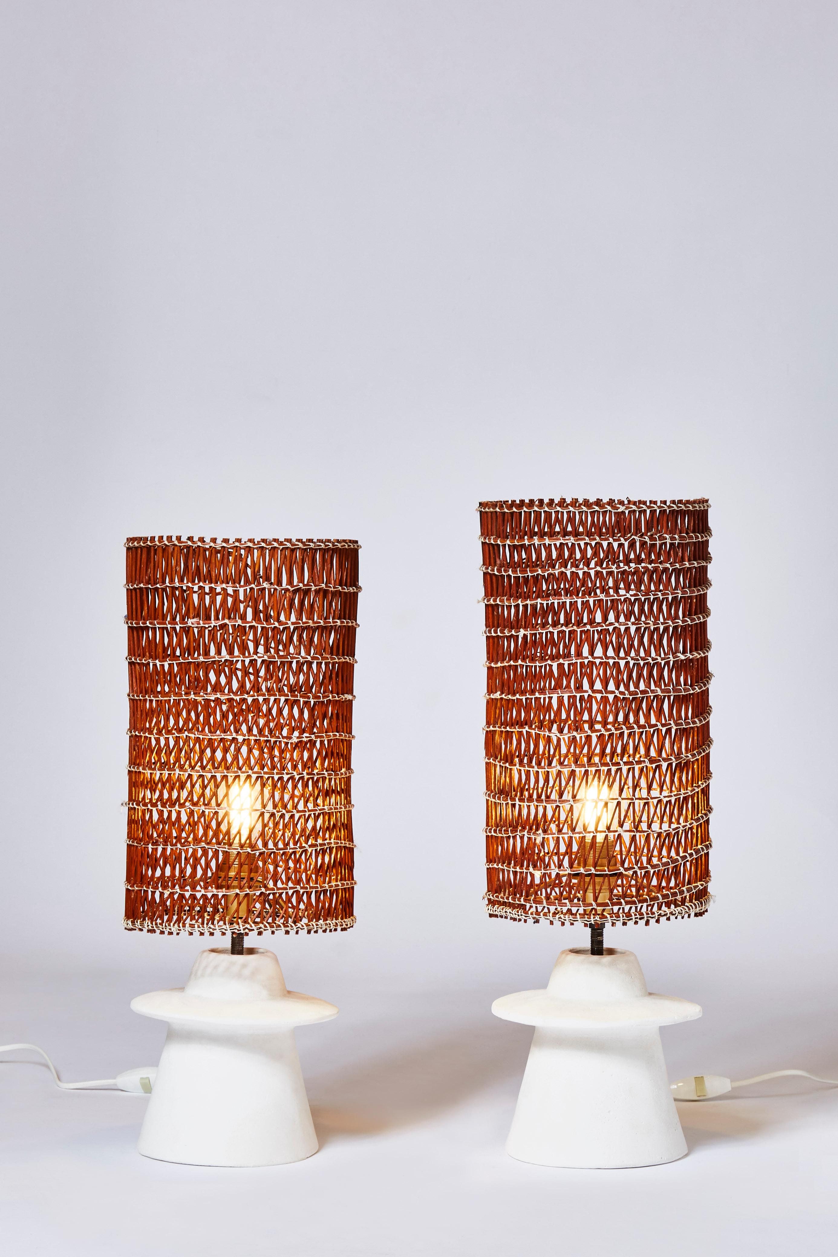 Pair of small plaster table lamps topped with handmade wicker shades.