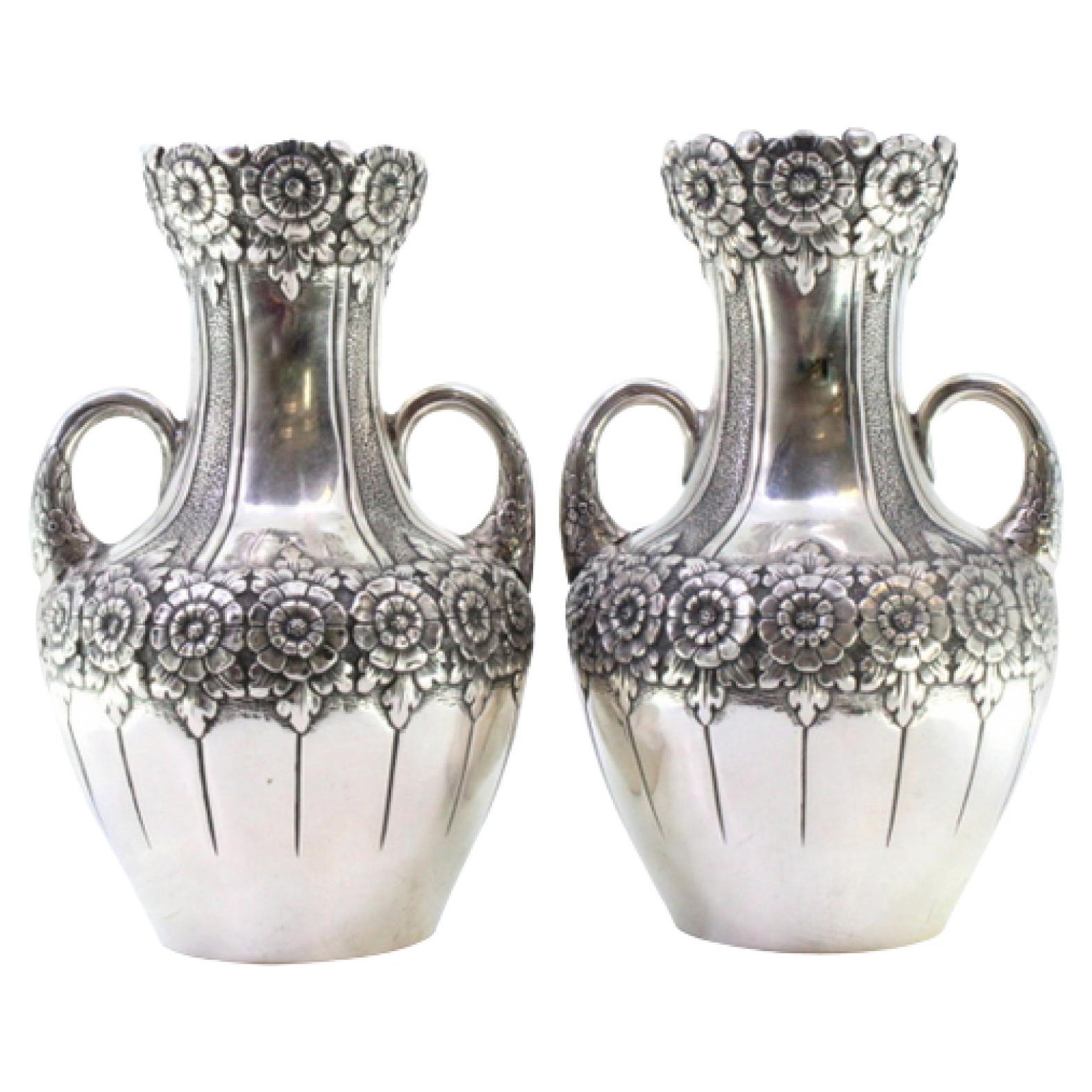 Pair of small silver jugs with floral motifs and embossed garlands