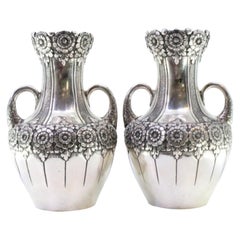 Pair of small silver jugs with floral motifs and embossed garlands