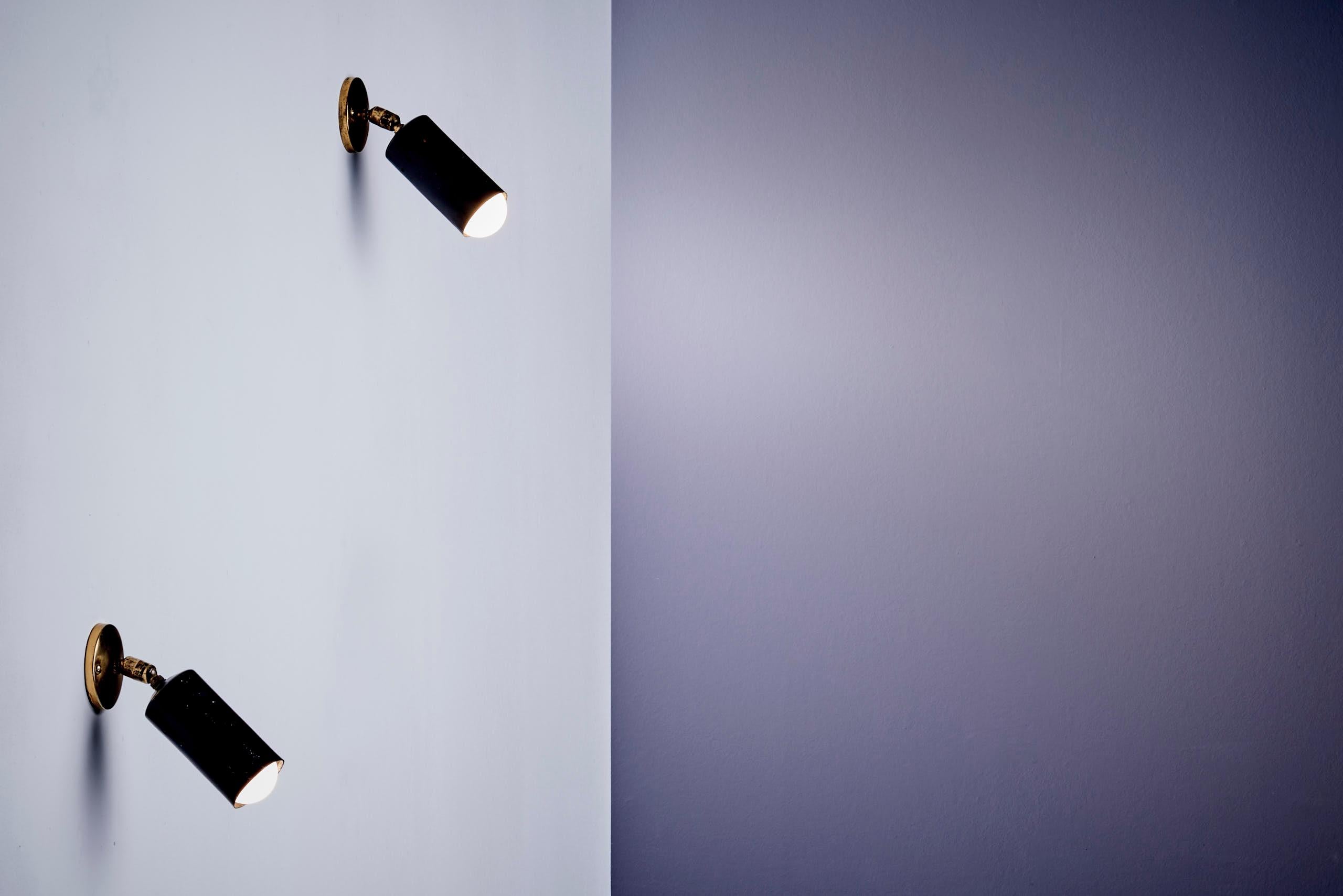 Versátil par de lámparas cilíndricas compactas de Parscot, ideales para montar en la pared o en el techo. Fabricada en latón con pantallas de aluminio pintadas de negro, cada luminaria se ajusta para dirigir la luz. En estado original, con pátina y