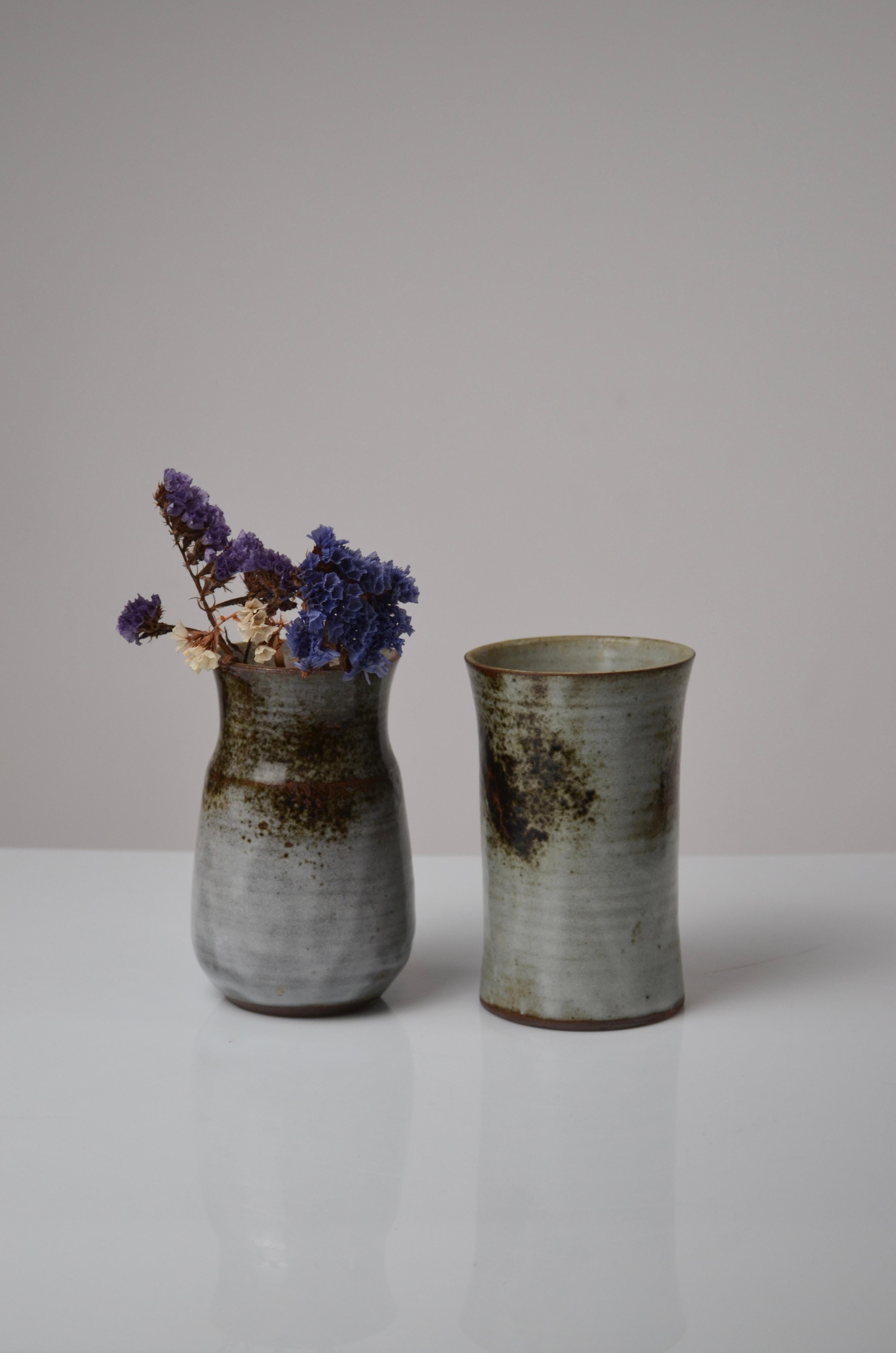 Elegante paire de petits vases en grès des célèbres céramistes français Thierry et Chantal Robert. Ces pièces présentent une surface subtilement émaillée dans des tons terreux de gris et de brun, avec de délicats reflets rougeâtres. 
De légères