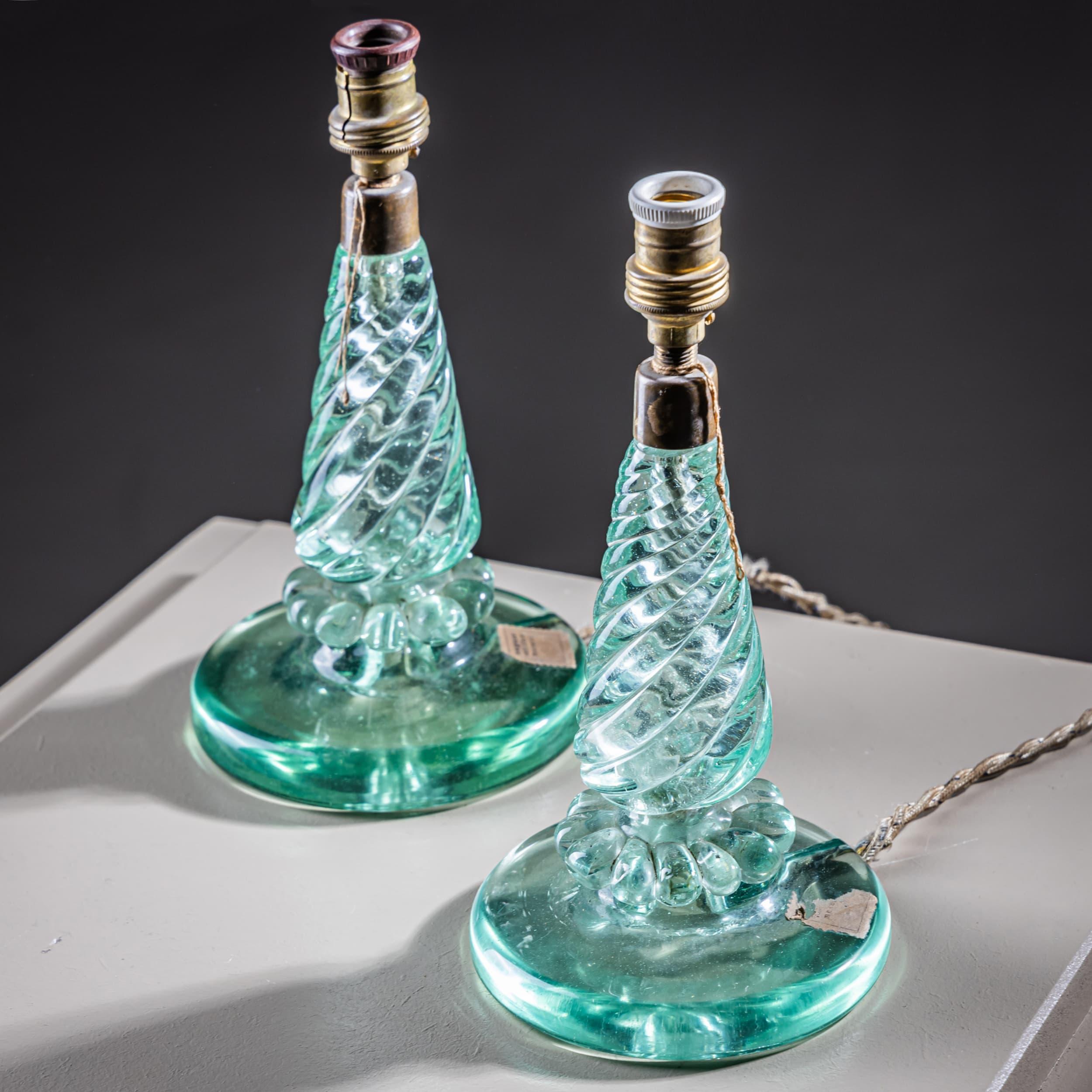 Paire de petites lampes de table décoratives avec des bases en verre teinté bleuâtre. La tige torsadée et la base ronde avec des motifs de pétales stylisés soulignent l'élégance du design. Les prises et le câblage d'origine sont restés intacts, ce