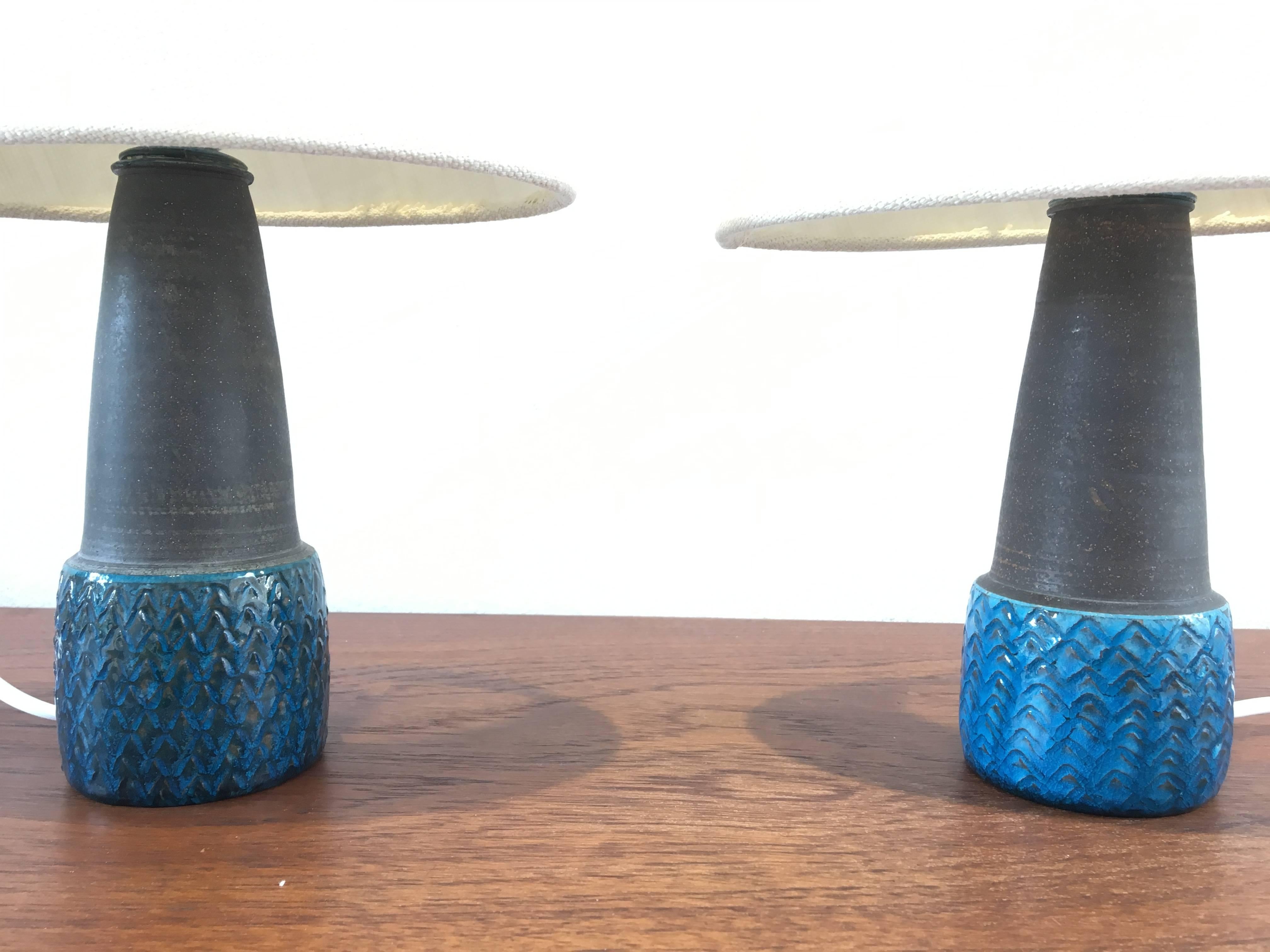 This pair of small stoneware table lamps was designed by Nils Kähler and made in the 1960s by Herman A Kähler Ceramic (HAK) in Denmark. Both lamps have colored glaze covering an geometrically shaped patterns. The top is made from unglazed smooth