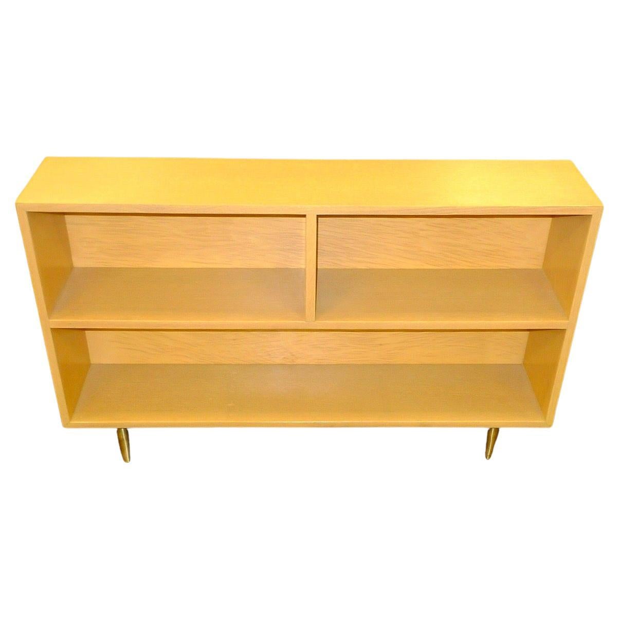 Pair of small blonde wood book shelves standing on four tapered brass legs by Widdicomb Furniture Co. attributed to Robsjohn-Gibbings (see closeup of section from original Widdicomb/Robsjohn-Gibbings Modern Originals product sheet).
I believe these
