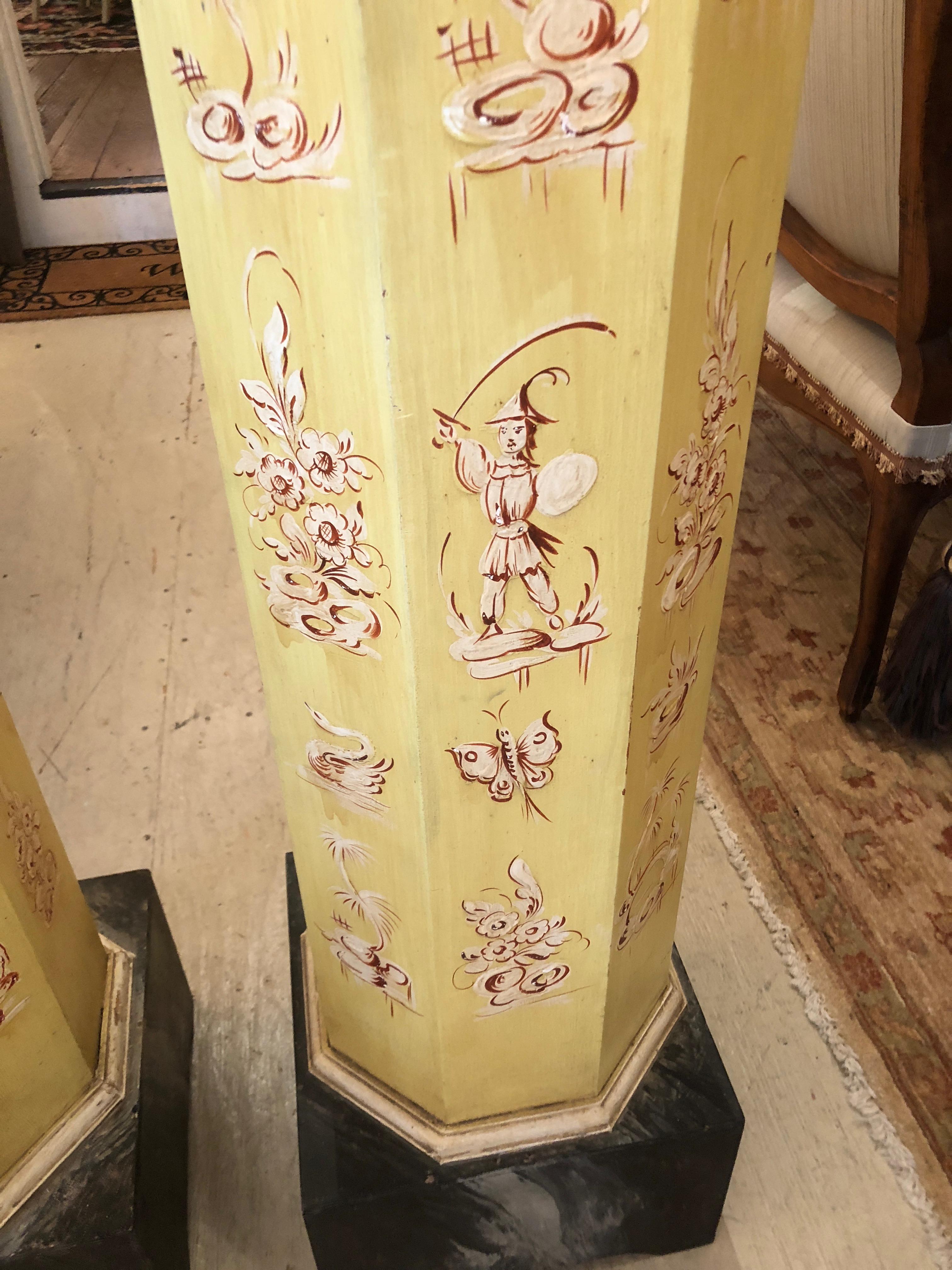 Two glamorous architectural decorative columns faux painted a light yellowish gold with burnt orange and cream toile like decoration, having black marbleized octagonal tops and square bases. Top surface is 11 x 11.