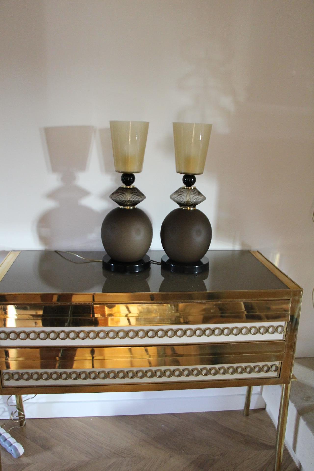 Cette impressionnante paire de lampes de table est fabriquée dans un très beau verre mat de couleur brun fumé. 
Sa base est faite d'une profonde pièce de verre de Murano noir brillant qui rappelle sa boule de verre noire supérieure. Son corps