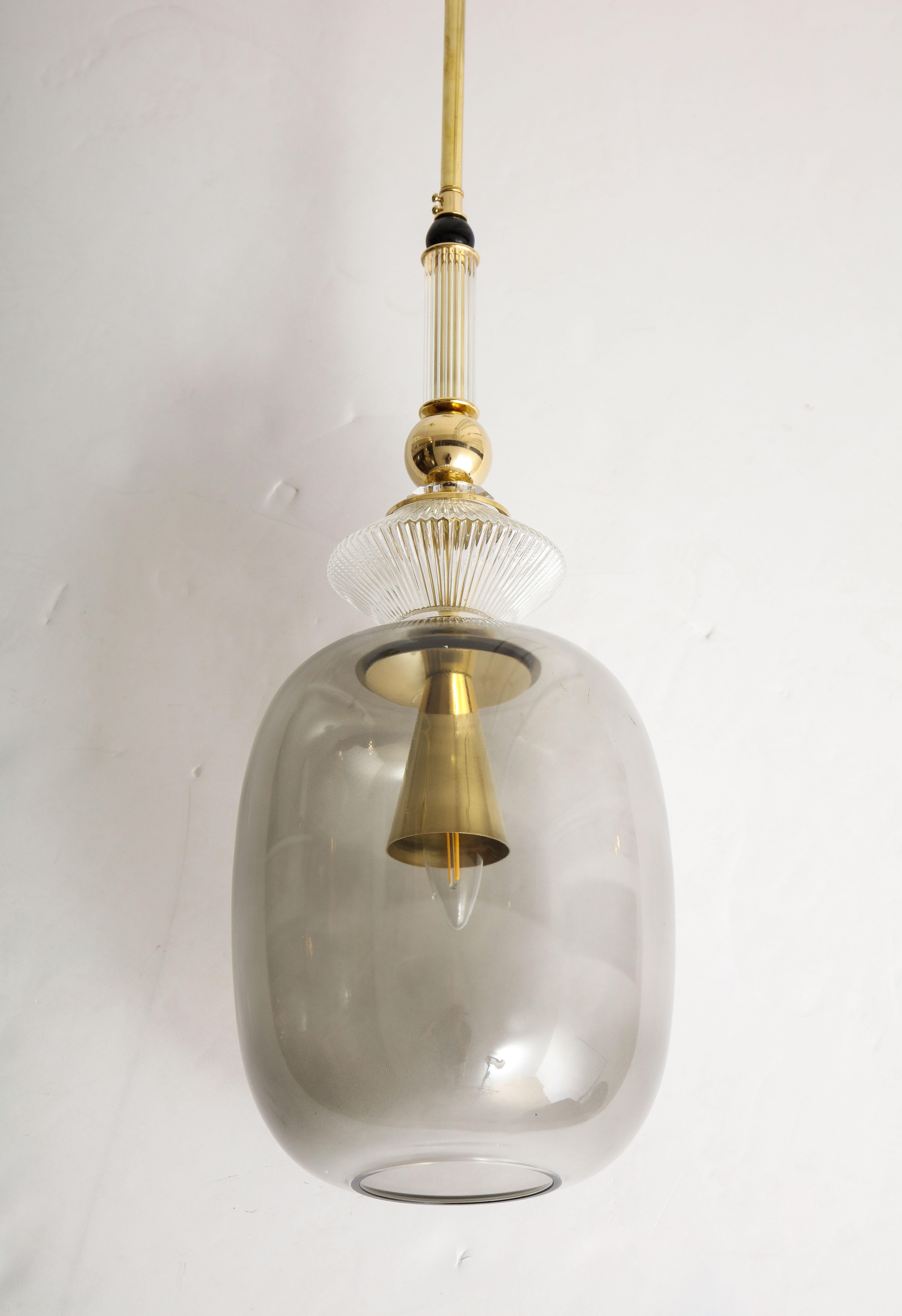 One of a kind pair of Murano glass and brass pendants, handmade in Venice, Italy. A smoked grey taupe Murano glass globe forms the base of this pendant with multiple Murano clear and textured glass elements and brass balls stacked above it. A