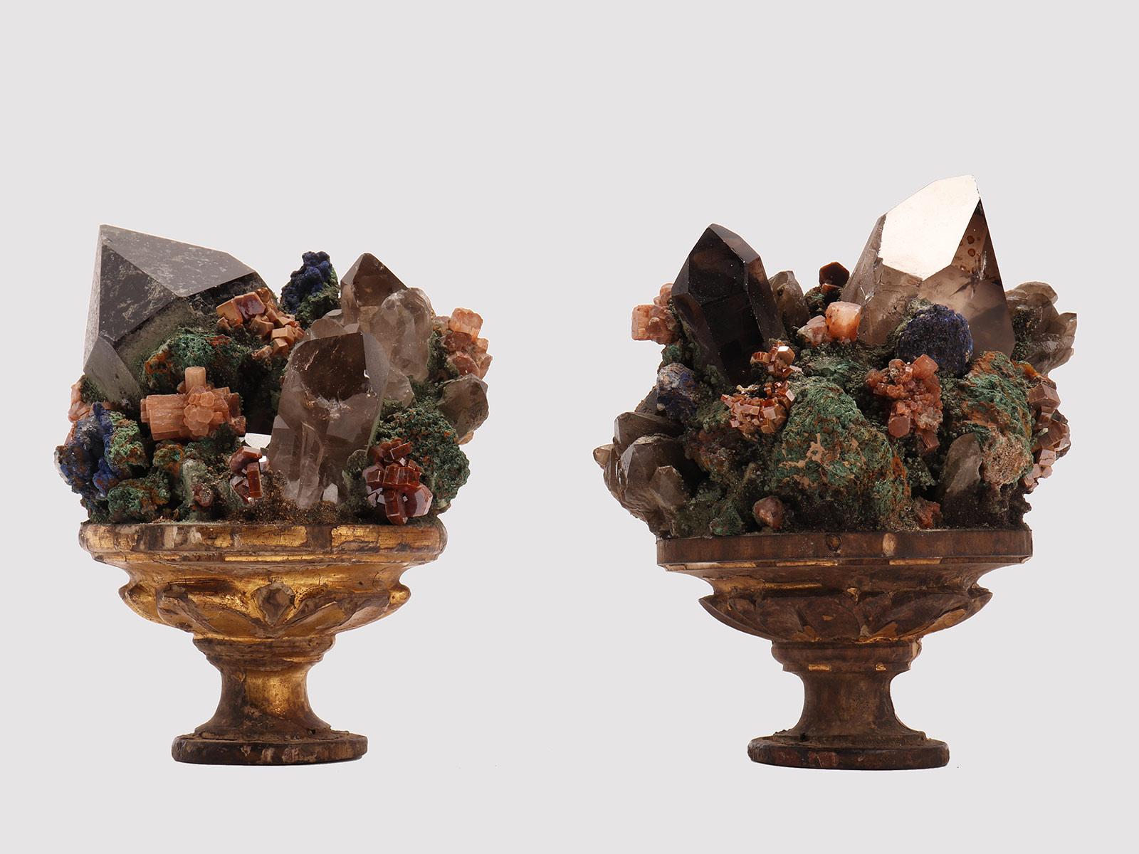 A pair of a naturalia mineral specimen. A composition with smoky quartz, vanadinite, malachite and native copper crystals, mounted over a gold plated wooden base with leaves. Italy circa 1880.