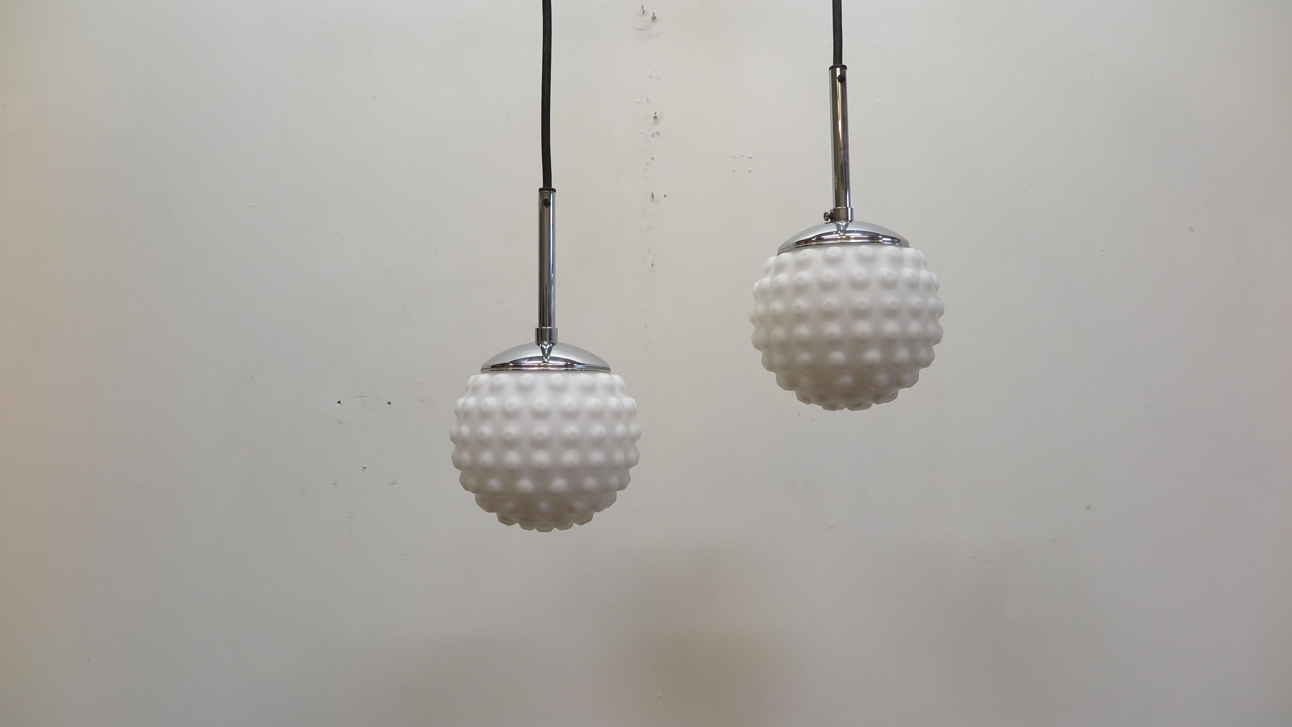 Pair of Mid-Century Modern Snow Ball pendant Lights with bubble texture. Frosted white molded glass snow ball pendants, Doria Leuchten, Germany 1970's. Chrome shafts supporting textured white glass Spheres. In very good condition. 
Height is
