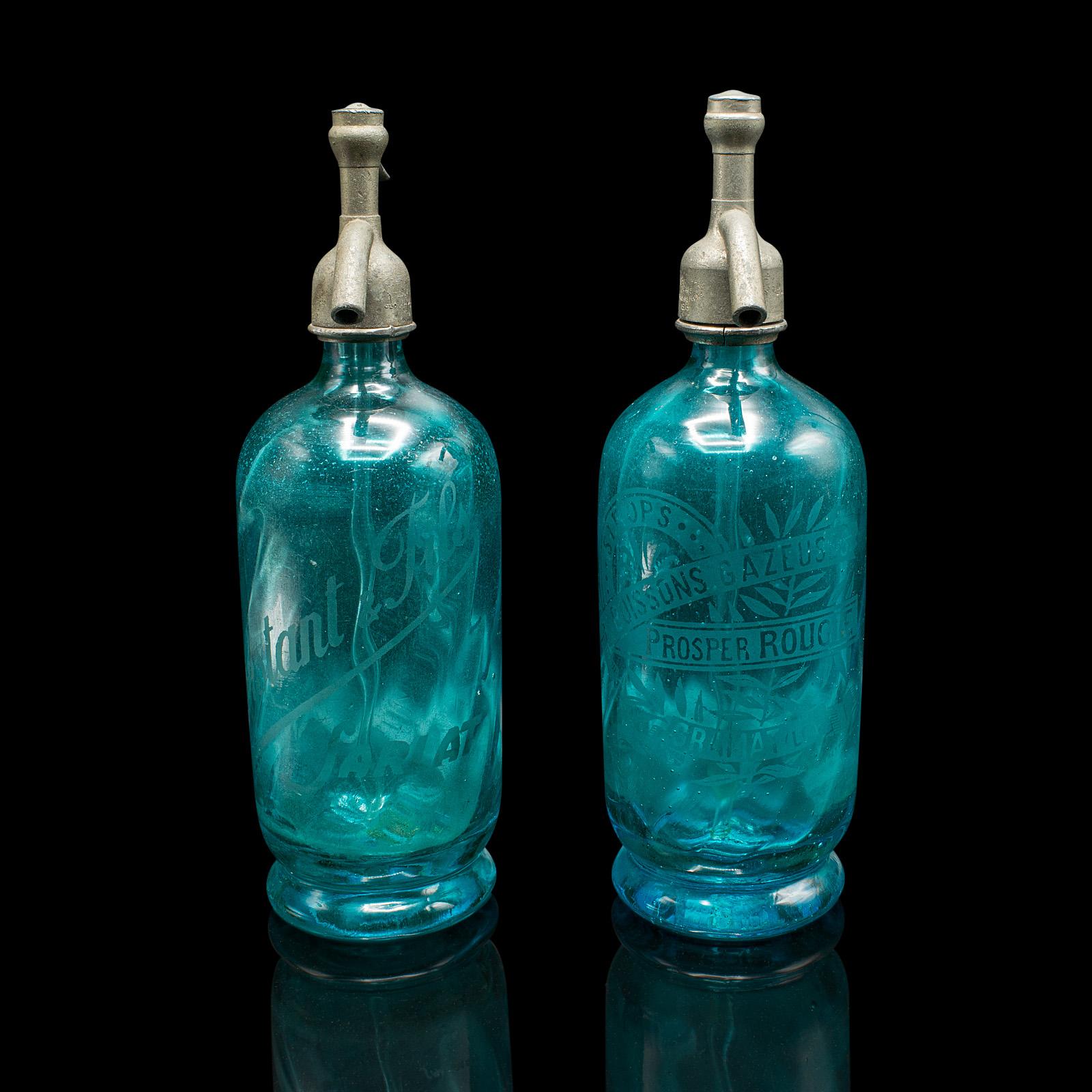 Dies ist ein Paar gealterter Soda-Siphons aus auffallend blauem französischem Glas aus dem frühen 20. Jahrhundert. 

Diese charmanten Seltersflaschen sind mit ihren leuchtenden Glastönen, dem geätzten Branding und dem Charme der damaligen Zeit