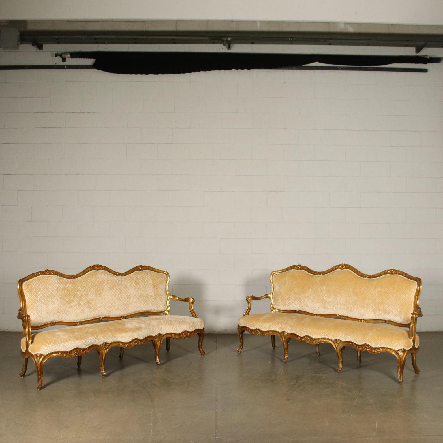 Pair of Barocchetto Neapolitan sofas, supported by eight curved and carved legs, the under-the-top shaped band is decorated with sun-shaped 
and rocaille carvings, represented again on the backrest, which is also curved; the armrests are shaped and