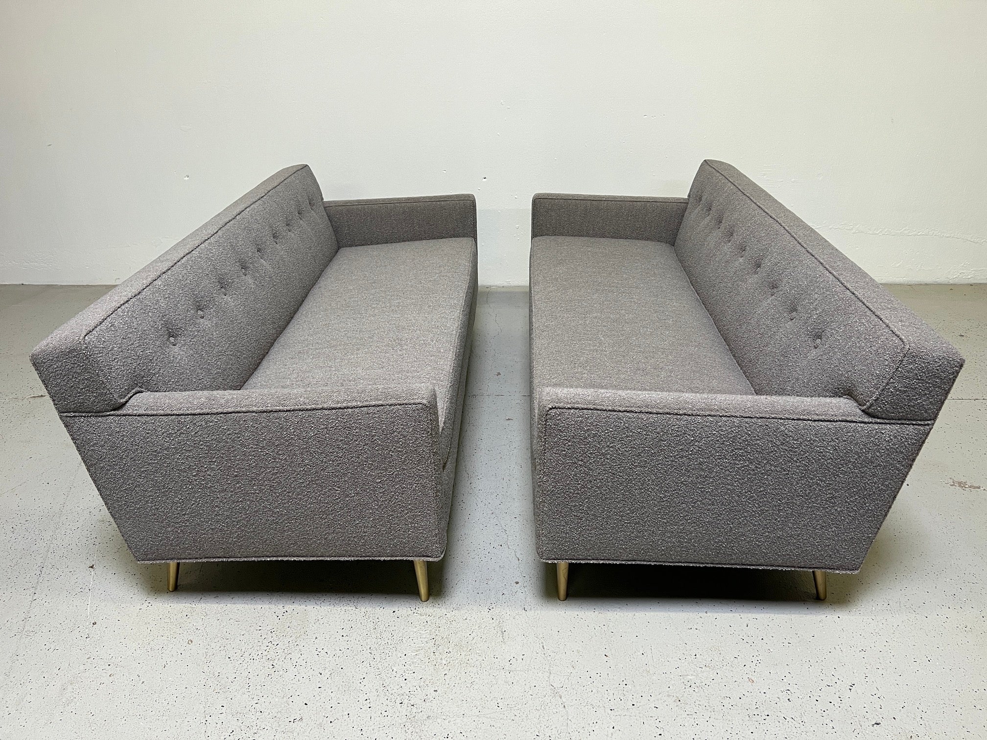 A matching pair of small sofas / settees designed by Edward Wormley for Dunbar.  Iconic form with tapered brass legs. Fully restored and upholstered in 
Designtex / Lambert / Smoke. 