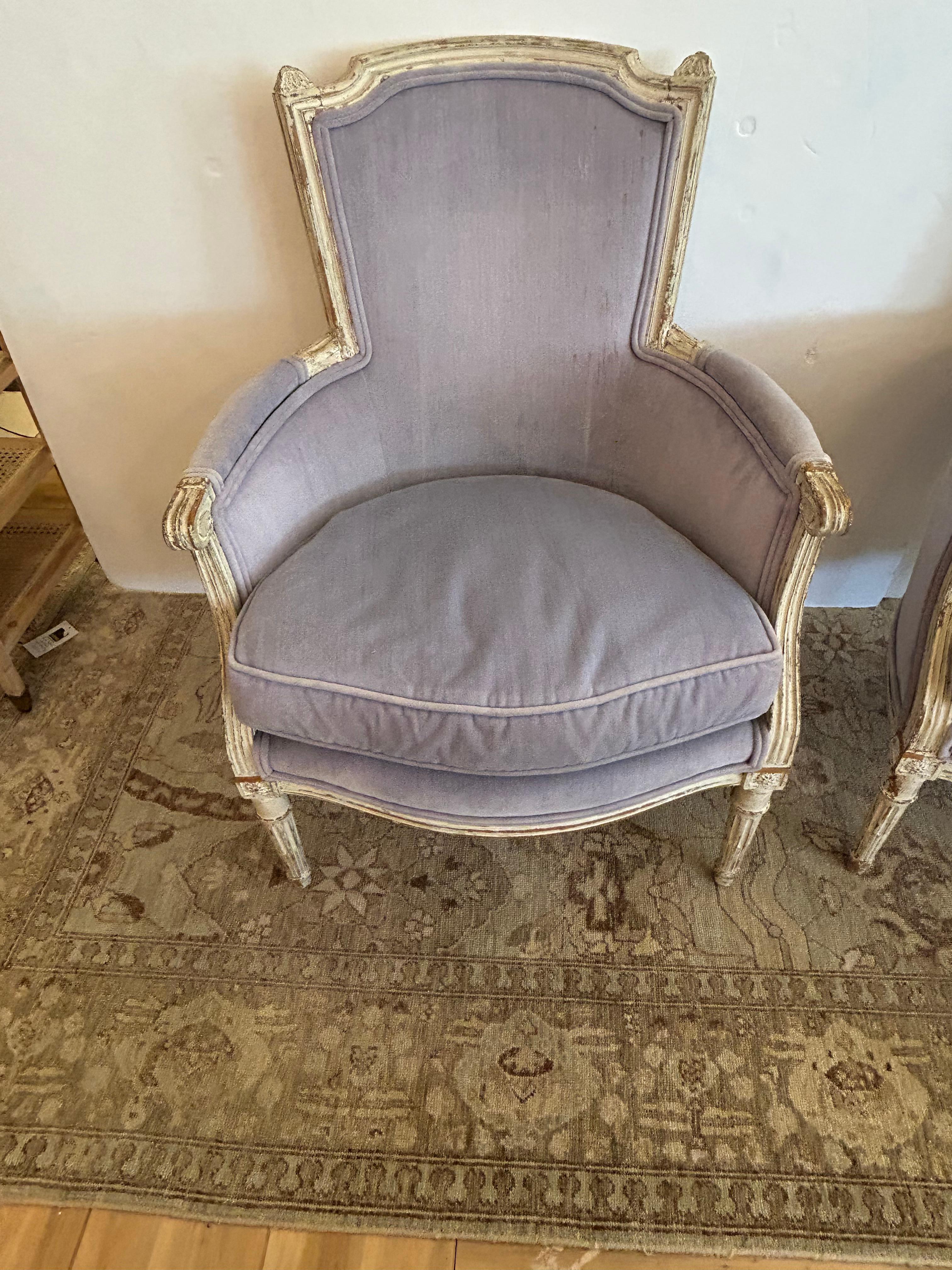 Romantic pair of beautifully weathered Louis XVI French bergeres having  painted chippy original patina and slightly faded soft periwinkle velvet upholstery.  Seat cushions are down filled.
Arm height 24