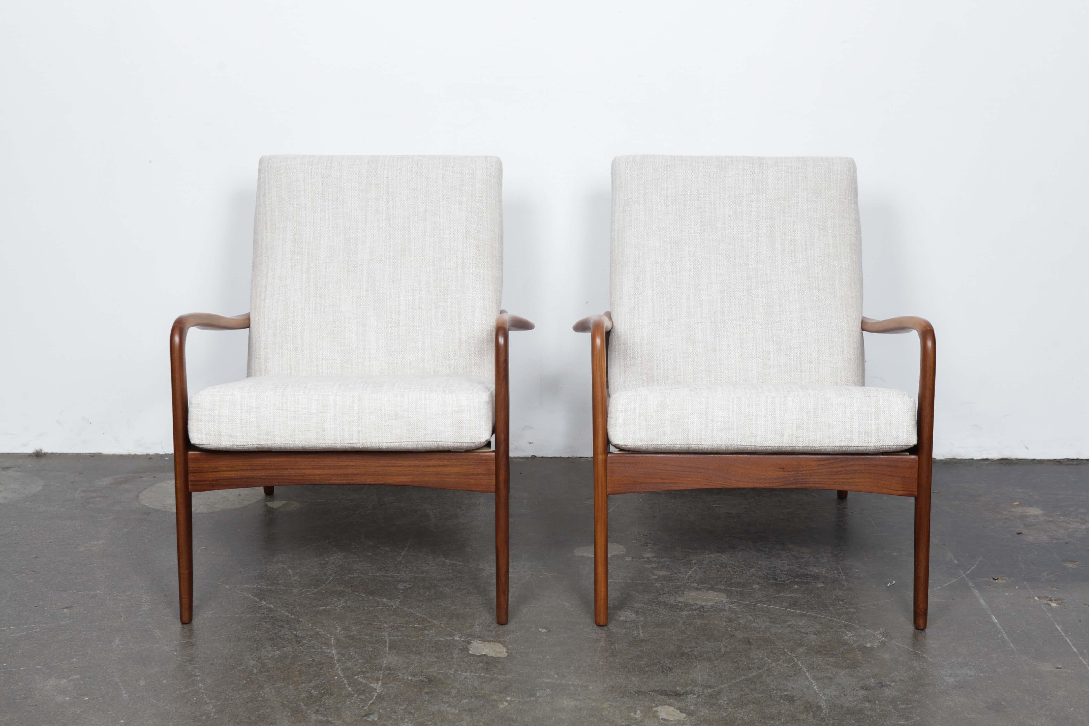 Matching pair of British midcentury lounge chairs by Greaves and Thomas, circa 1960s. Lovely swooping arm design on these pieces. Newly refinished solid afromosia teak wood frames with newly upholstered back and seat done in an off-white Belgian