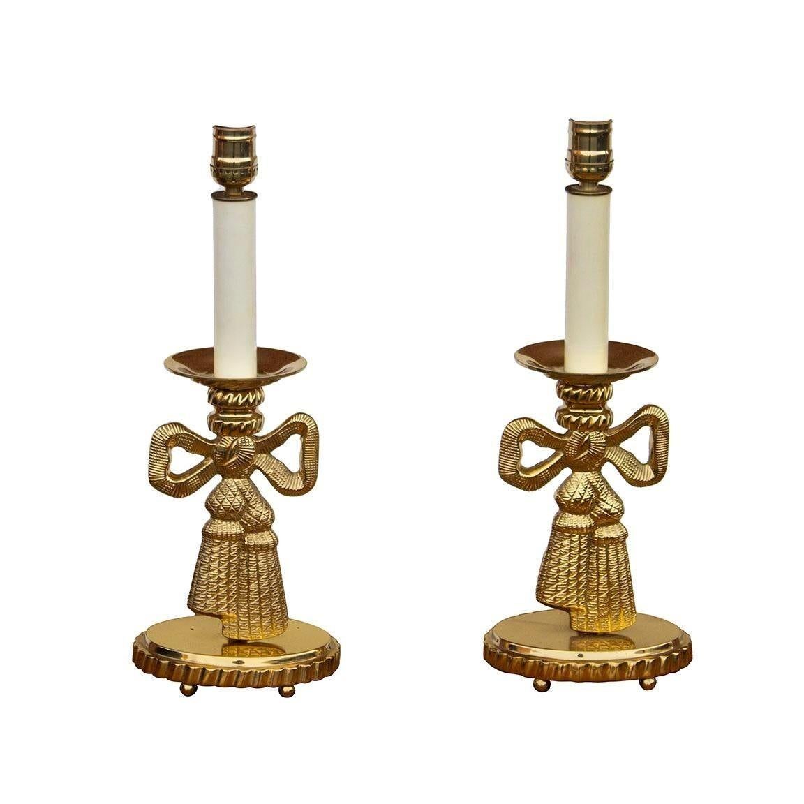 USA, 1980s
Pair of solid brass candlestick table lamps made by Top Brass. Each table lamp has brass ball feet and a weighted base, a polished brass upper with cream colored socket, original oval black paper shades that clip on to the bulb, and