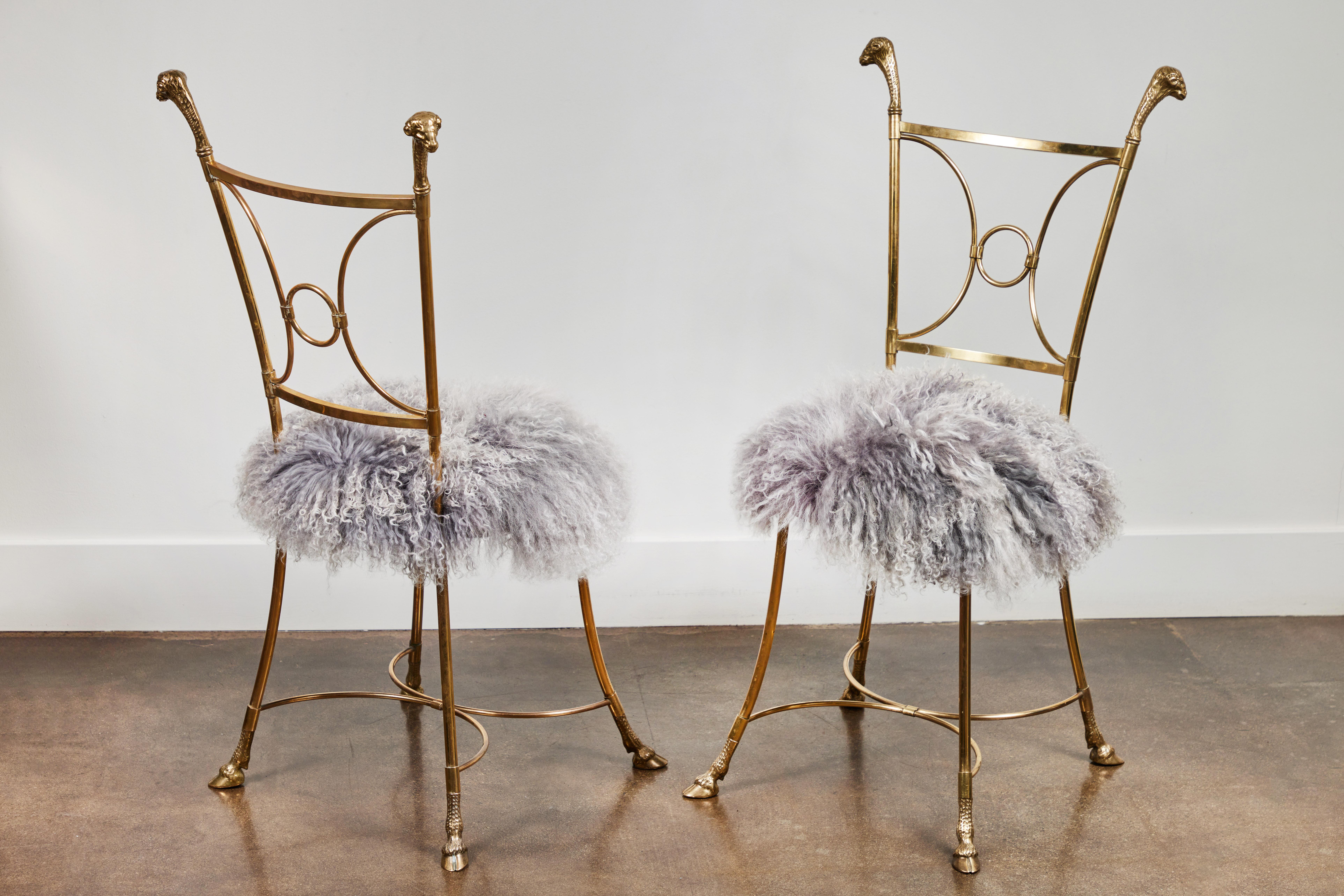 Fabulous pair of heavy, solid brass chairs in the neoclassic style with ram's head details in the manner of Maison Jansen. Professionally polished and newly re-upholstered in Mongolian curly lamb.