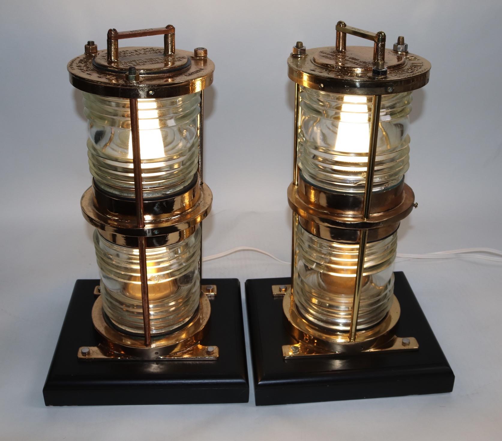 Pair of solid brass maritime beacons with double Fresnel lenses set into heavy brass beacon housings. Both are recently wired for home display and are mounted onto thick wood bases with rich dark finish. Weight is 60 pounds the pair.