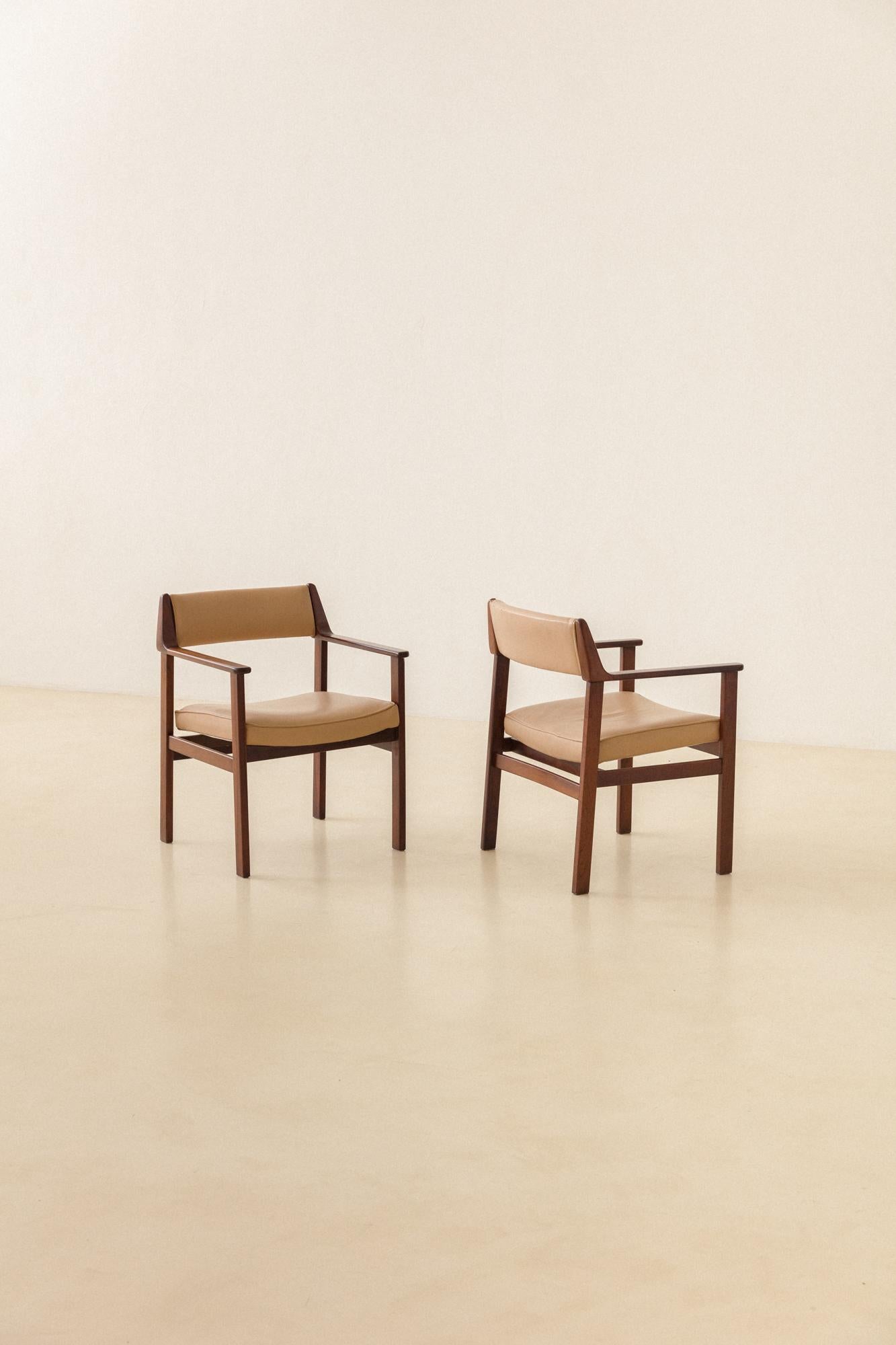 This pair of gorgeous chairs with Armrests are made in solid Rosewood and leather, and was produced by the Brazilian company Casulo in the 1960s. 

Pieces are made of solid Brazilian Rosewood original upholstery in synthetic leather. The chairs