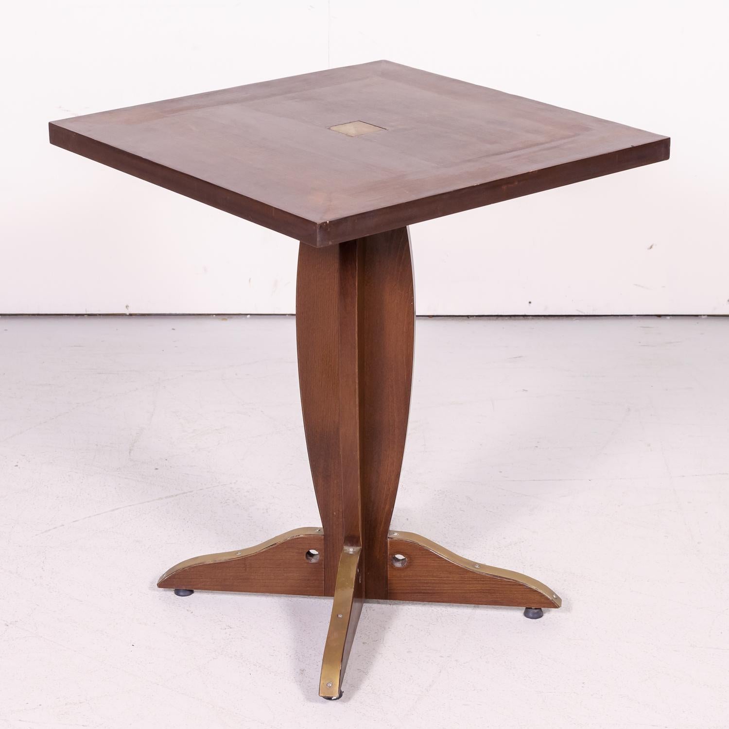 Pair of solid walnut French Art Deco period bistro tables having square walnut tops with center brass squares, circa 1920s. Raised on a walnut pedestal base with four feet having brass accents on top. Perfect for indoors or a covered outdoor area.