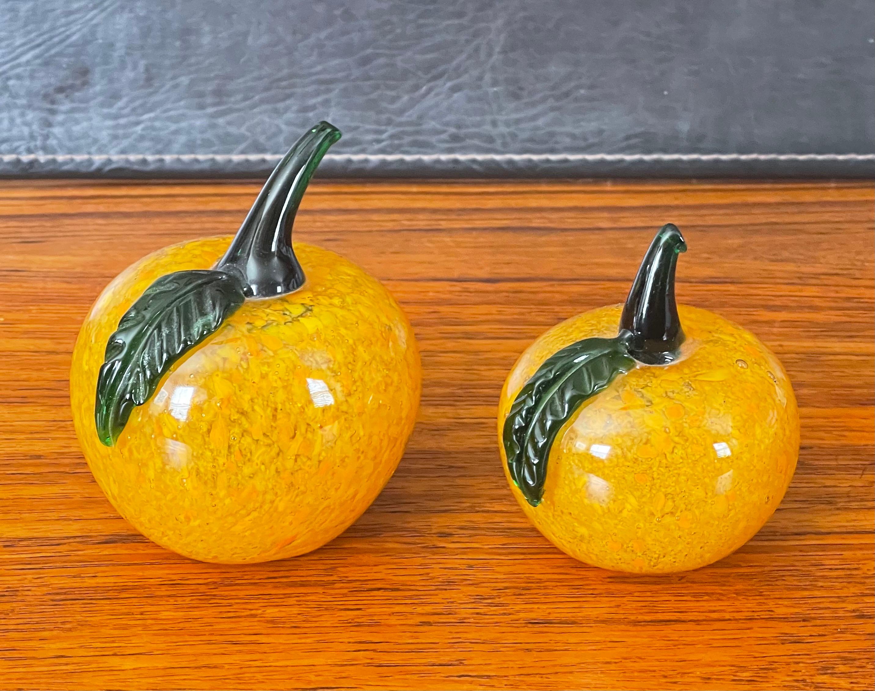 Nice pair of sommerso art glass pumpkins by Murano Glass Studios, circa 1970s. The pair are in very good vintage condition with no chips or cracks and have an orange sommerso style glass with deep orange, yellow and black speckles. The larger