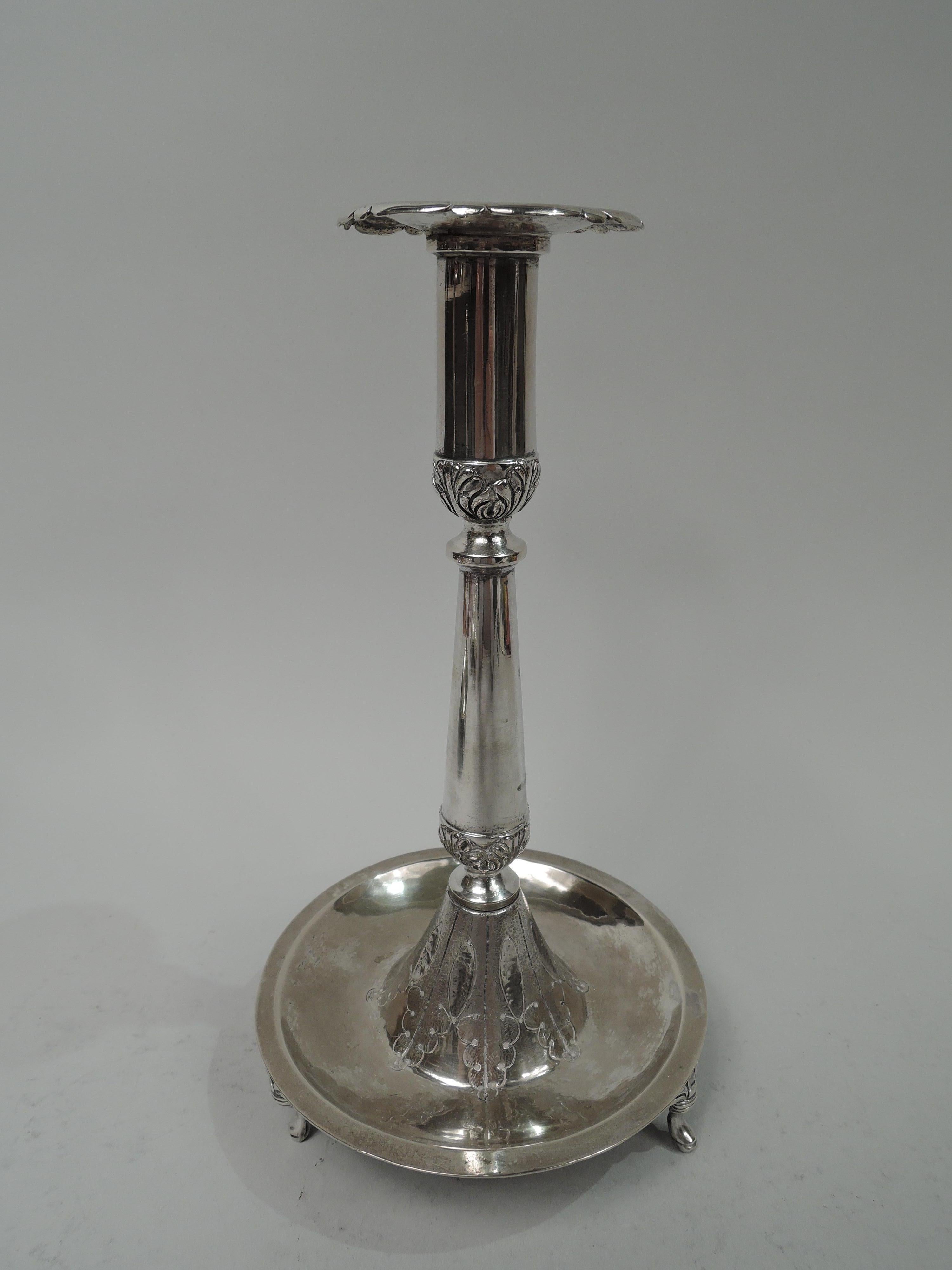 Pair of South American Classical silver candlesticks, 19th century. Each: Tall and upward tapering socket with scalloped bobeche on baluster shaft; domed foot set in round and concave base. Three leaf-mounted scroll supports. Tooled leaf borders at
