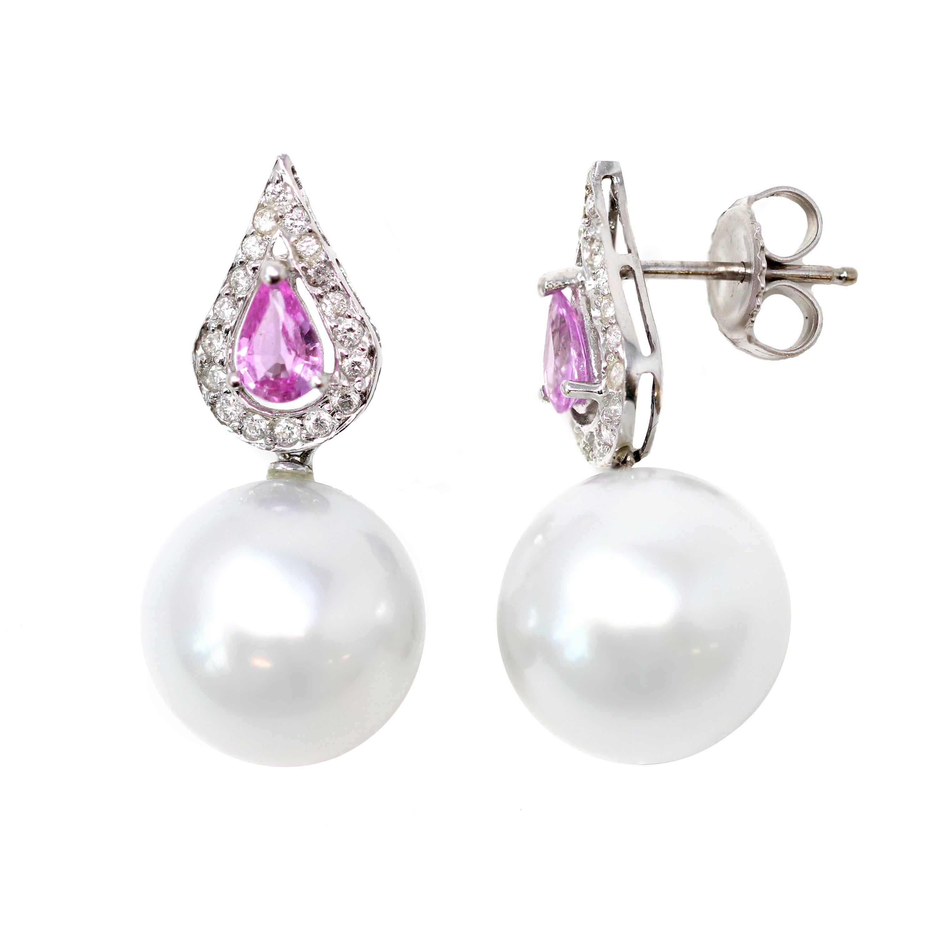 A pair of contemporary South Sea Pearl dangling earrings with Pink Sapphires and Diamonds, in 18K white gold. Made in the US, this pair of dangling earrings dazzles us with their 13.5 mm white round shape South Sea Pearls with excellent luster and