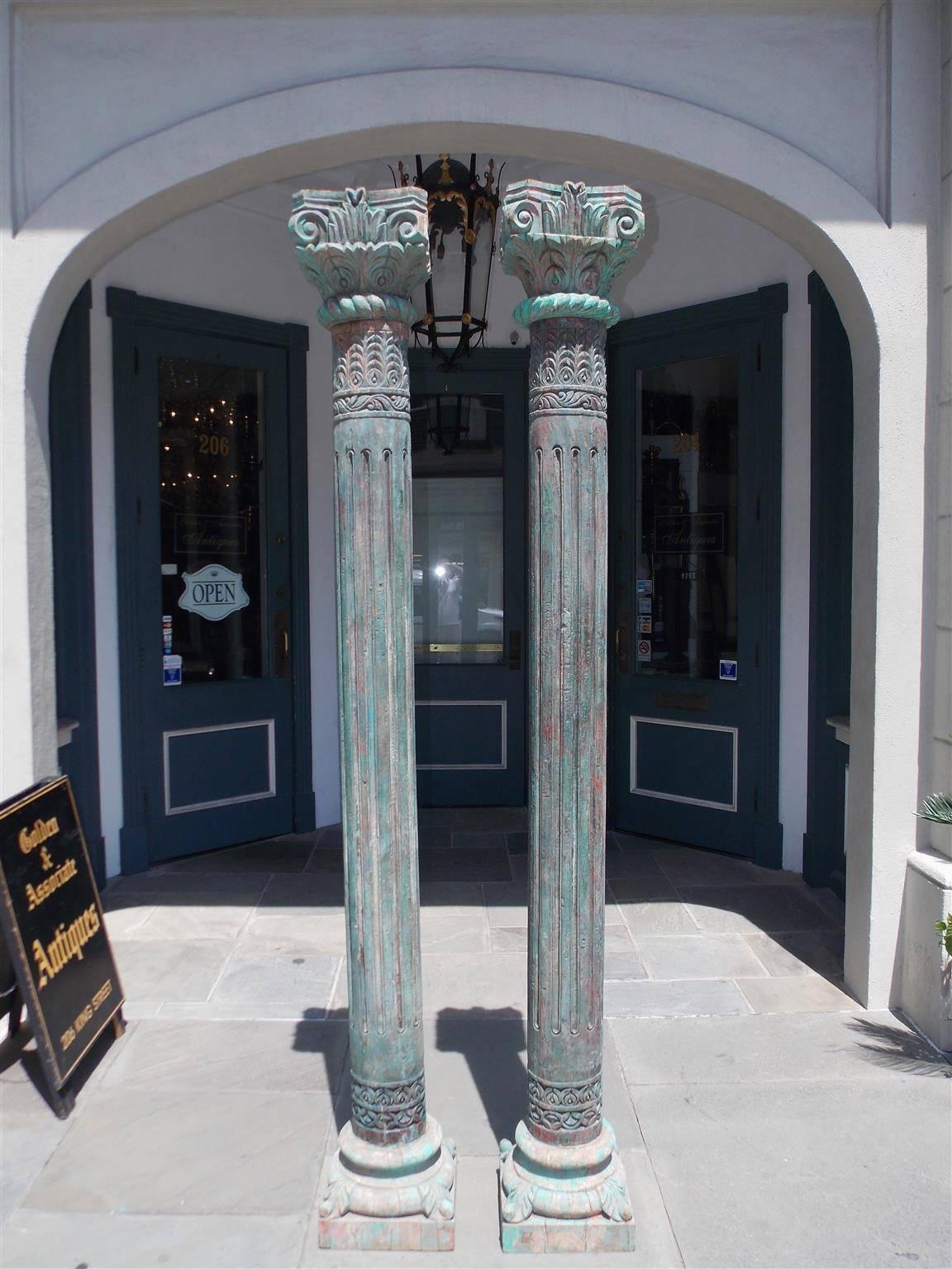 Pair of Southwest Asian carved wood and poly chromed columns with stylized Corinthian capitals, reeded pillars, and terminating on circular squared decorative floral plinths, Early 19th century.