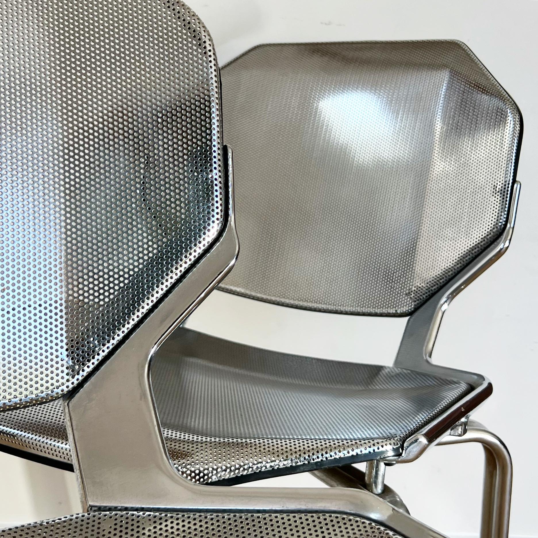 A pair of Italian space age metal chairs d’après Fröscher, early 1970s. Polished steel with rubber lining and featuring perforated seats and backrests. Each with molded manufacturer’s label « Fixtures Furniture » (shown in photos). Faint signs of