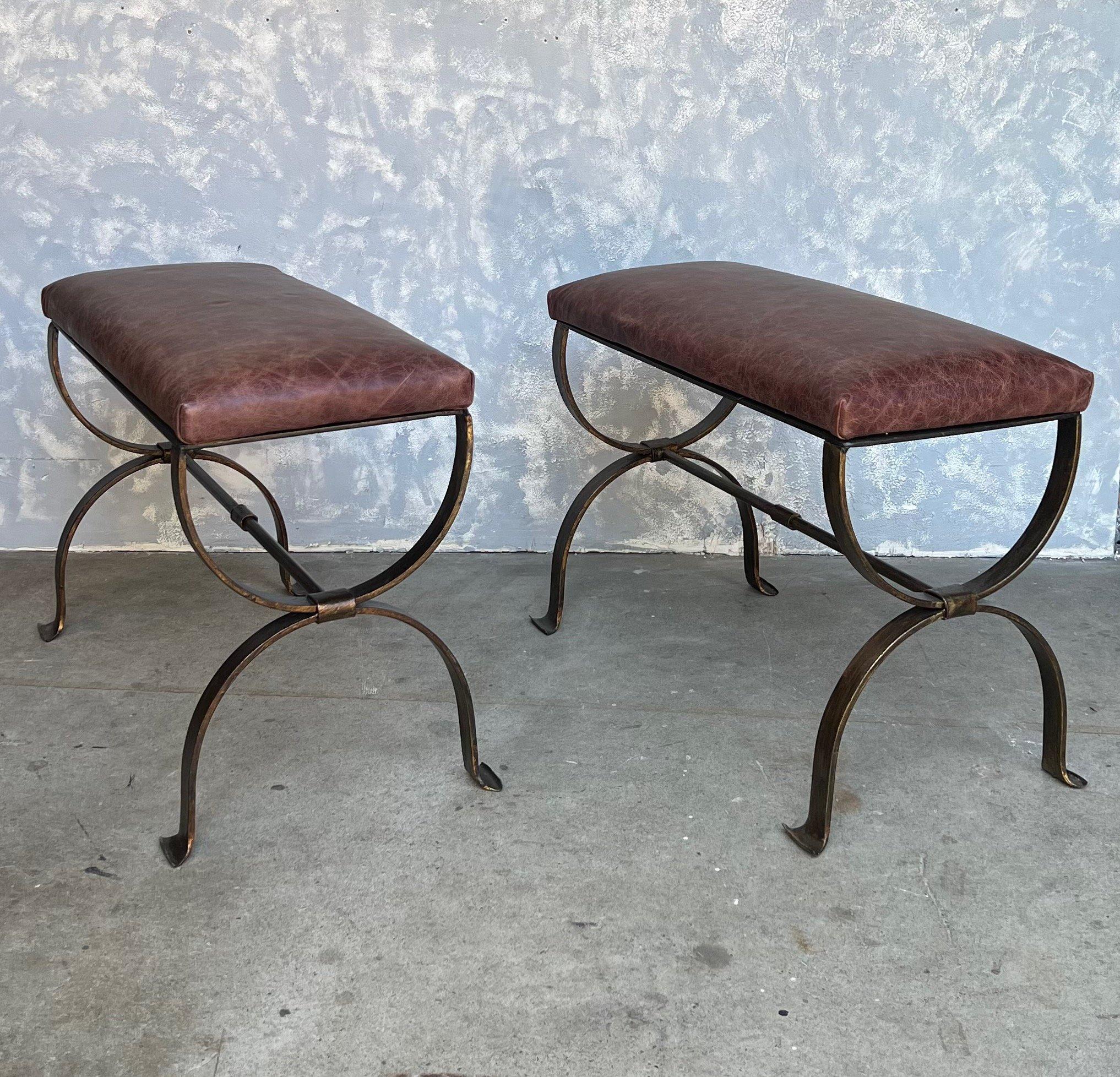 This pair of Spanish 1950s benches, made from gilt iron, holds an elegance that is both timeless and distinctive. The hourglass frames, central stretcher, and gently curved feet each contribute to its unique vintage charm. The iron frames are