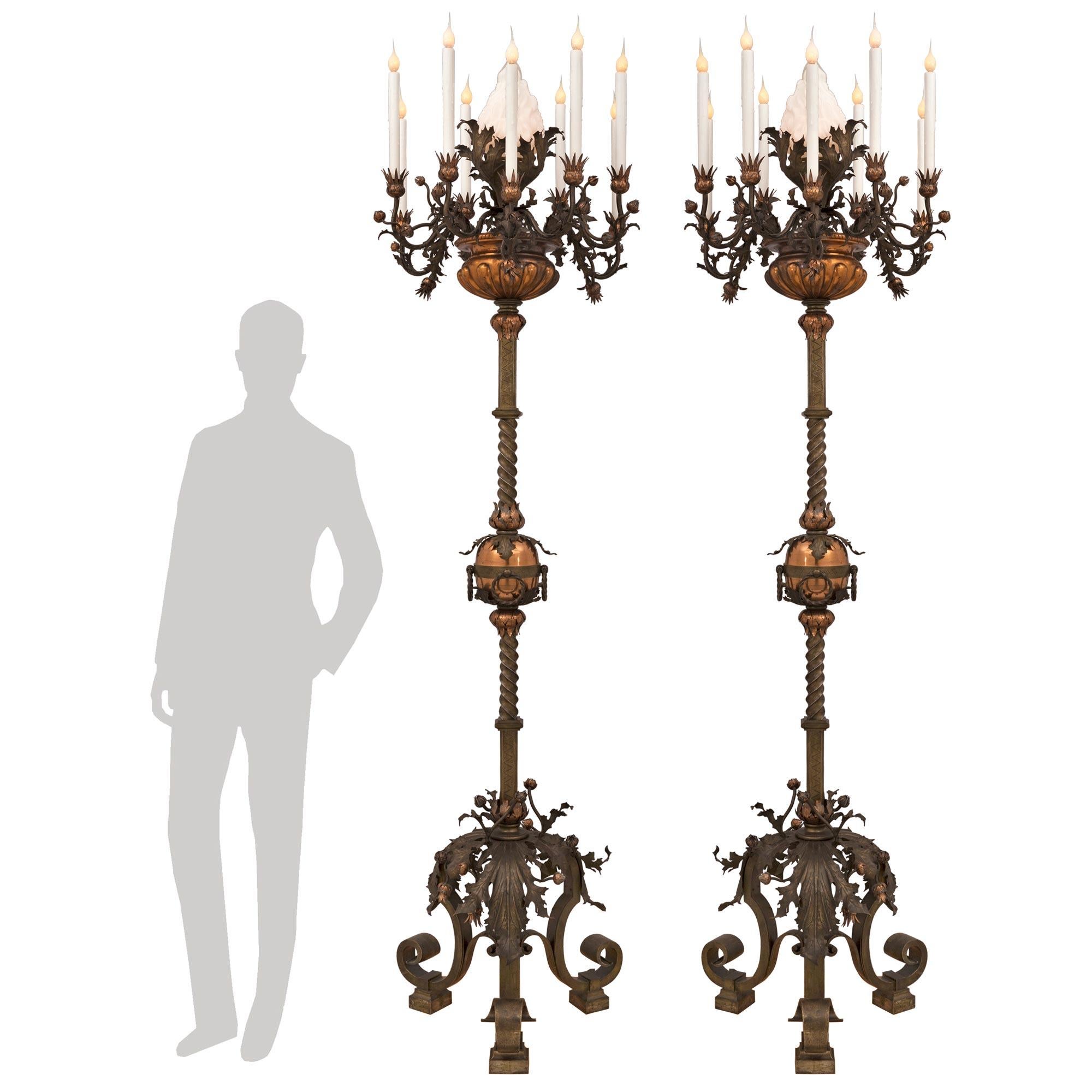 A stunning and palatially scaled pair of Spanish 19th century patinated bronze and copper Torchière floor lamps. Each most unique and extremely decorative ten light torchière is raised by an impressive 'S' scrolled tripod support with block feet and