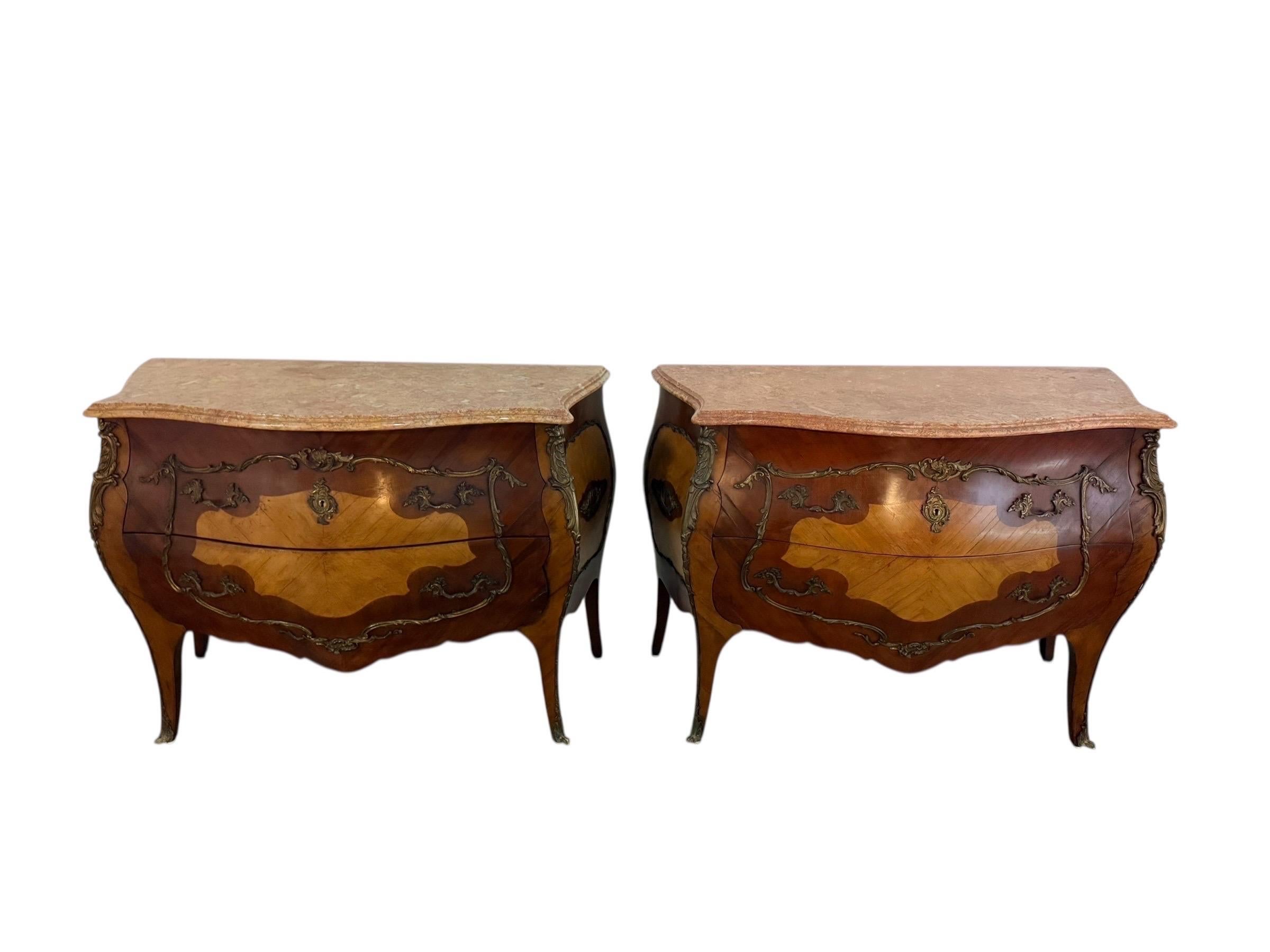 A fine pair of Spanish bombe-form chests, each surmounted with a shaped Portuguese marble top. The richly veined marble features soft tones of rose, cream, and taupe, with one top showing a slightly more faded surface from years of natural use and