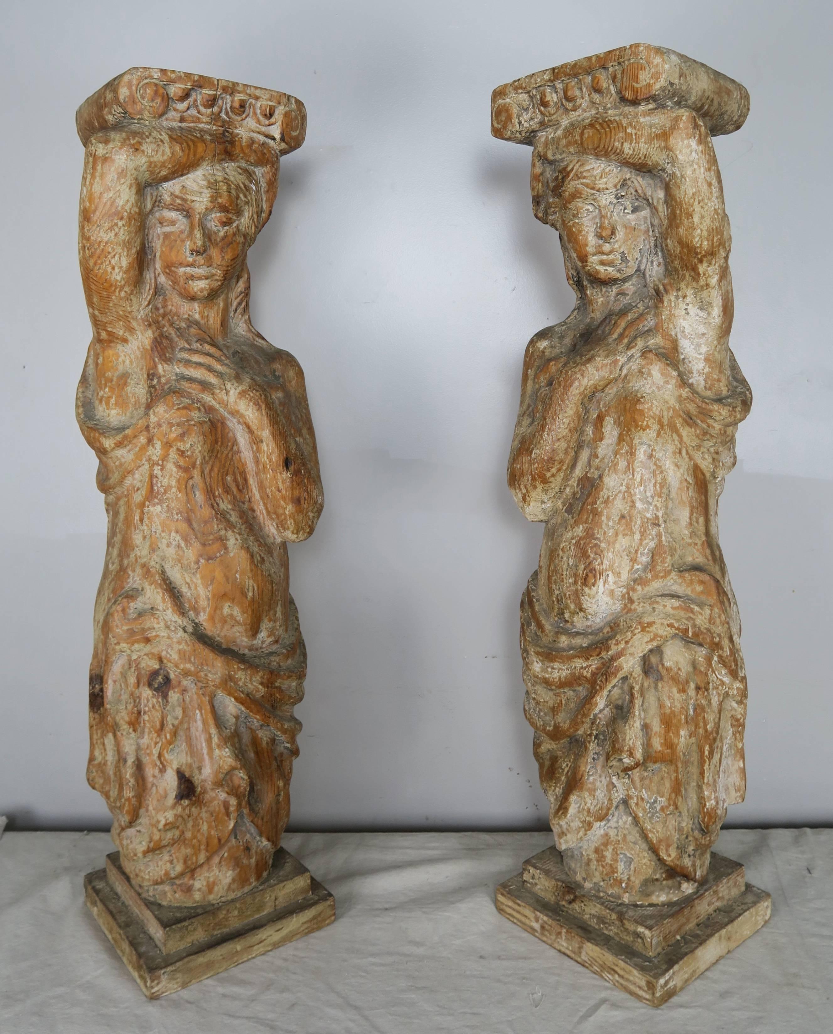 Pair of beautiful Spanish opposed carved wood figural pedestals. The pedestal can be used to hold planters of chunky candles. The pair of pedestals could also be the base to a console table or sofa back table.