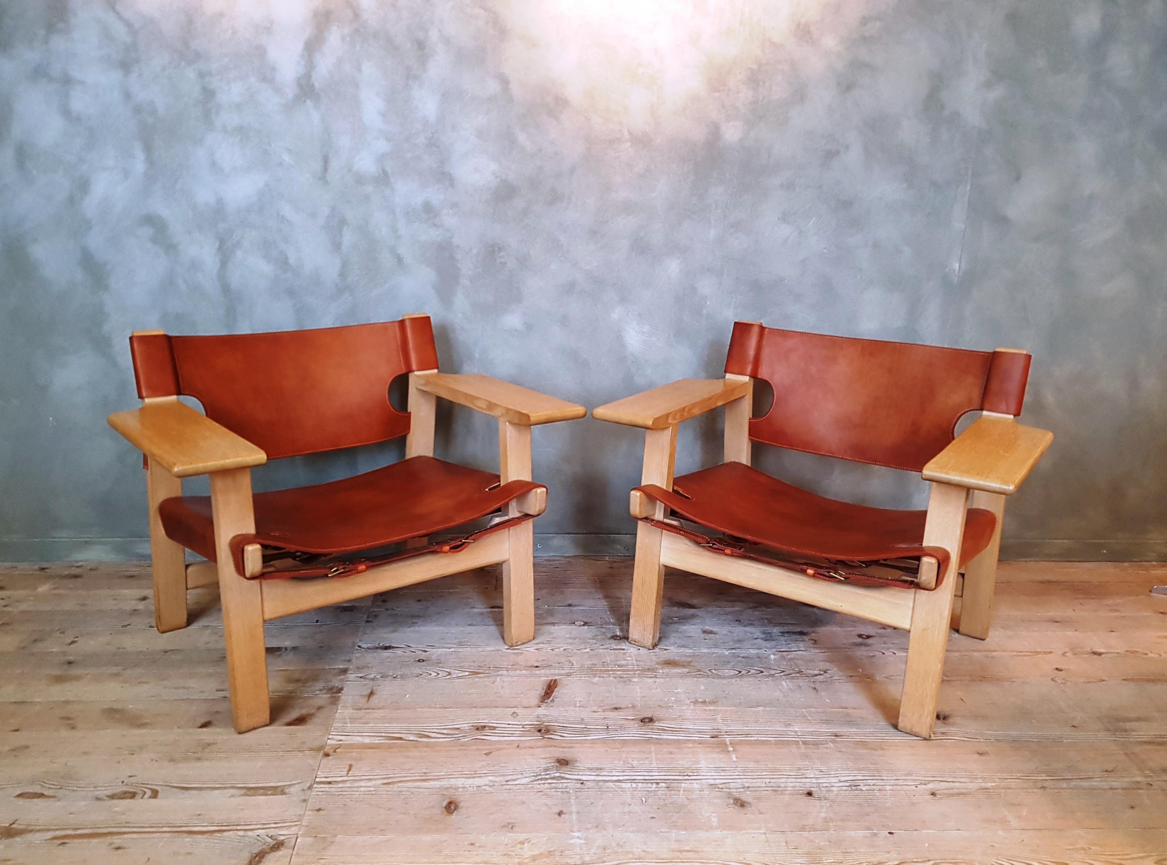 The Spanish chair was designed by Børge Mogensen for Fredericia. It is made of solid oak and saddle leather with brass belt buckles. The wide armrests provide storage space.
This pair of Spanish chairs are in a very good condition, the leather has