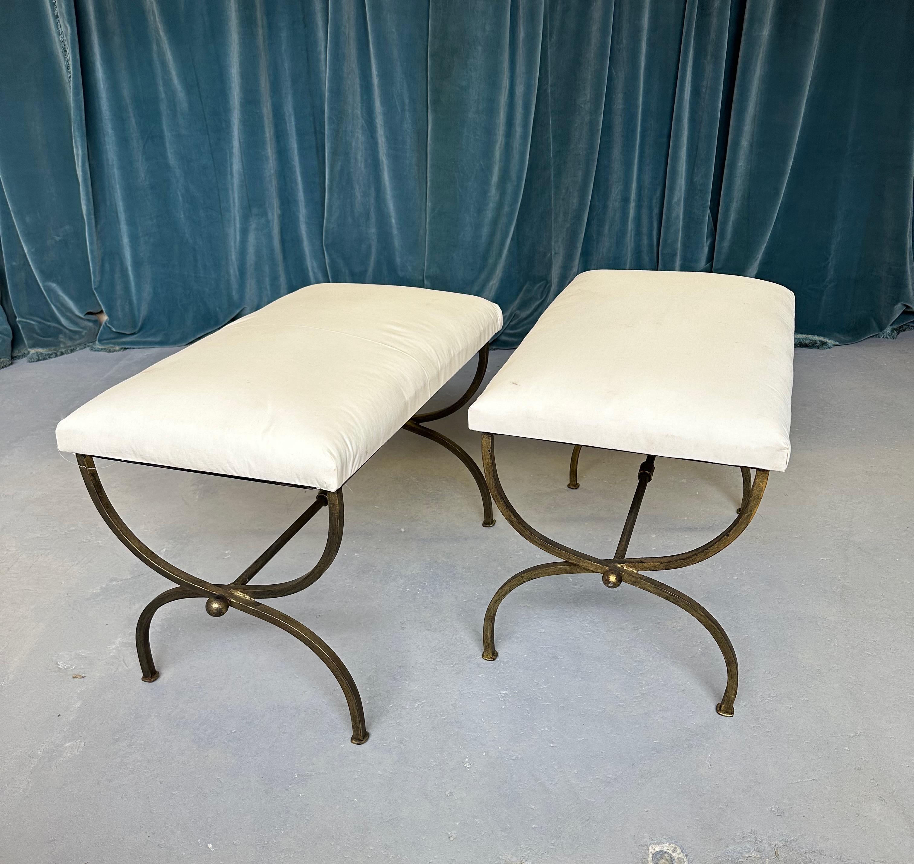 Une belle paire de bancs en fer de fabrication récente avec des pieds gracieusement courbés et des brancards centraux qui présentent un anneau central décoratif et des sphères aux extrémités. Fabriquée à la main par des artisans européens experts,