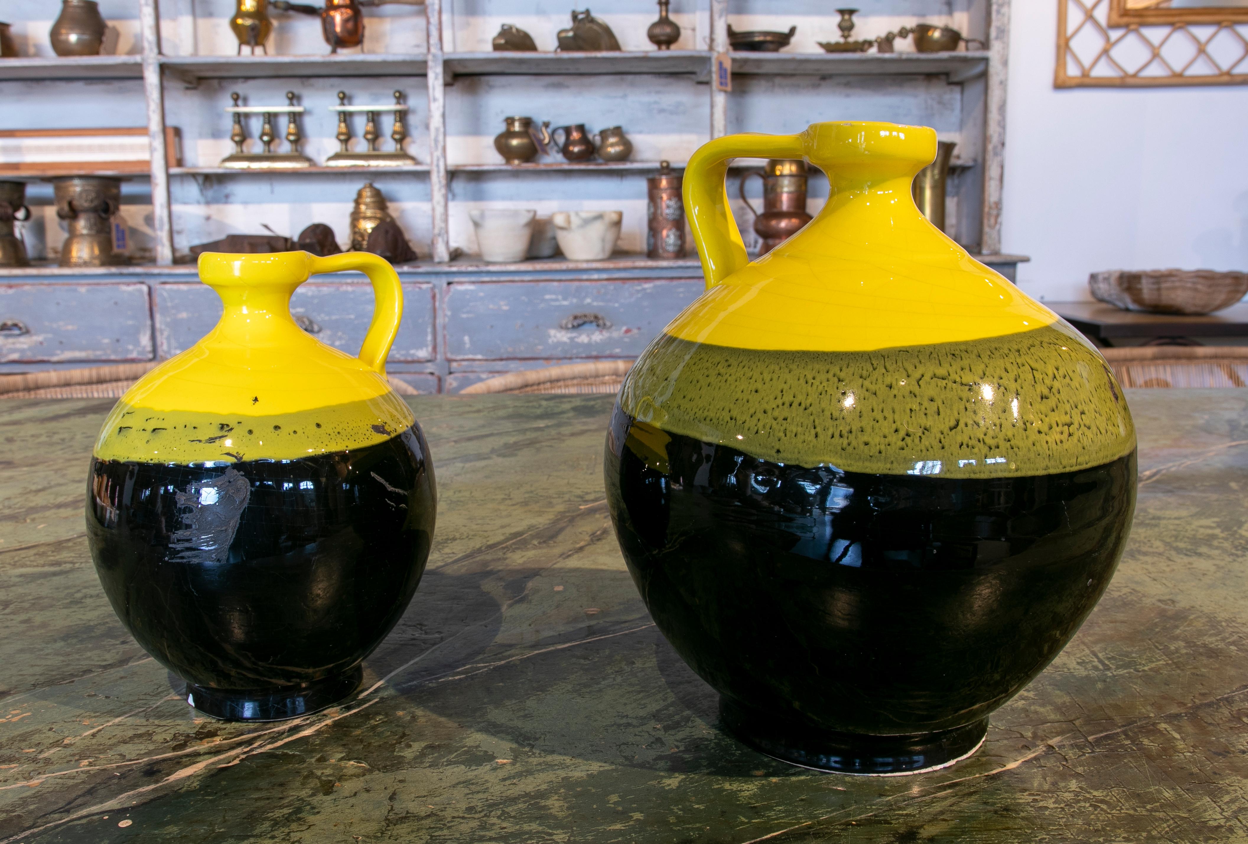 Pair of Spanish glazed ceramic jug with handle in tones of black and yellow.
