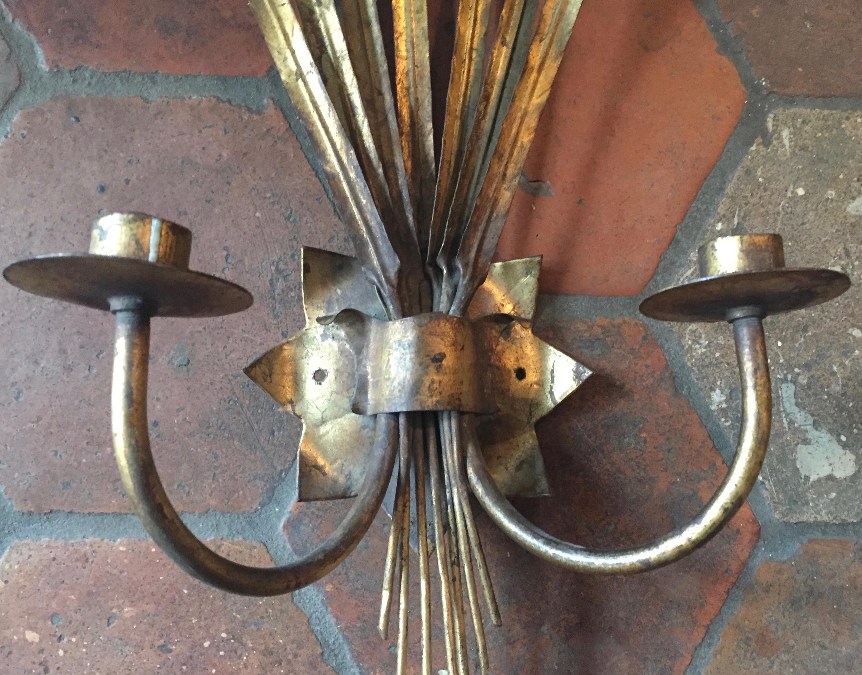 Pair of Spanish sconces, circa 1940. Handmade from tole and wrought iron and finished in hand applied gold leaf. Originally made for electricity but the wires have been removed to be used with candles. We can provide a quote to rewire them with new