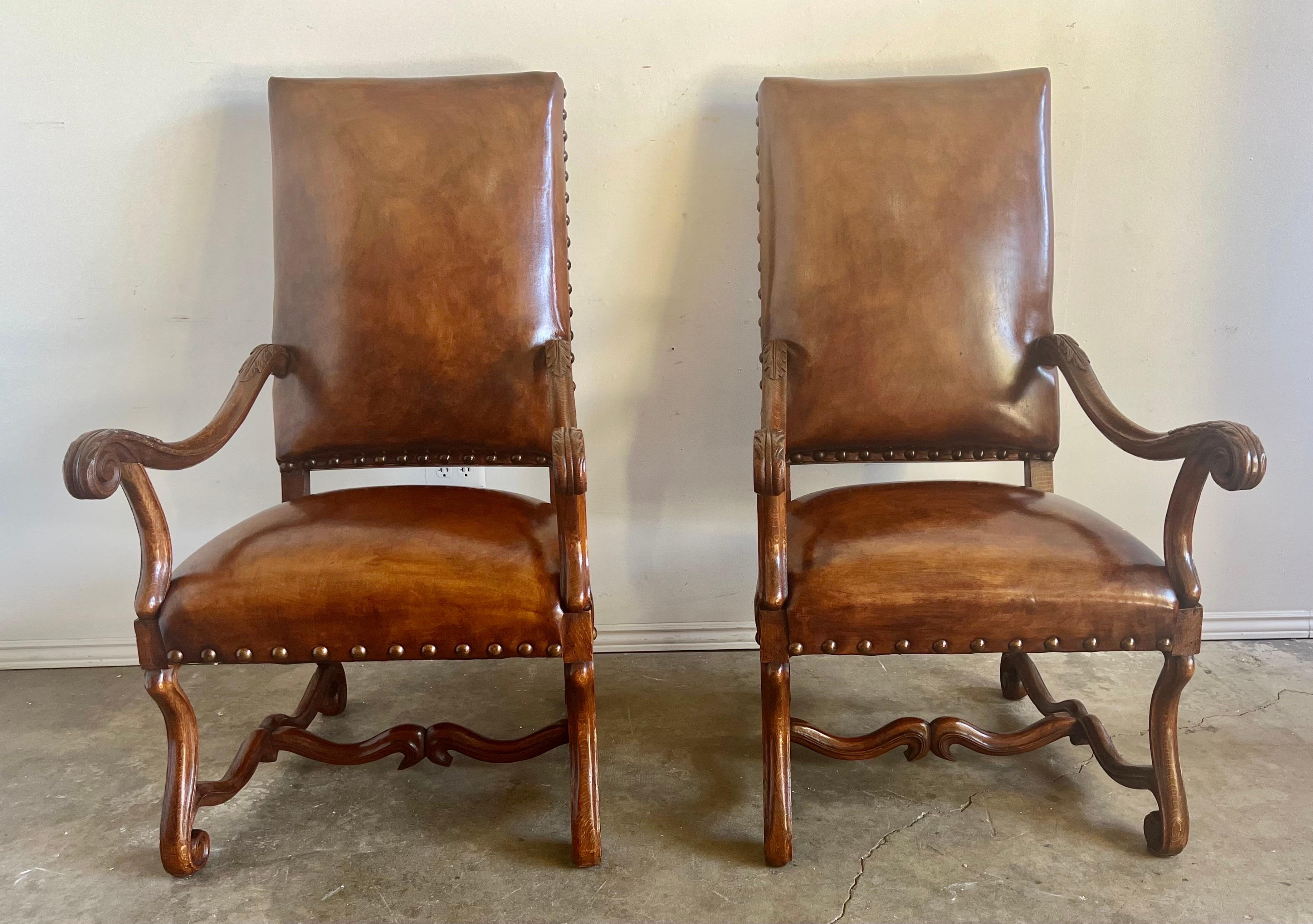Pair of grand scale leather armchairs upholstered in Tobacco colored leather and finished with nailhead trim detail.