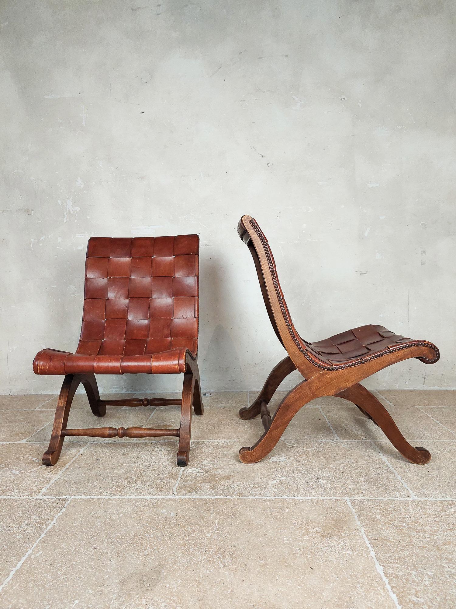 Pair of Spanish leather 'Slipper chairs' by Pierre Lottier for Valenti, 1940-1950s. Low vintage armchairs / fireplace chairs made of brown oak wood with and original cognac woven leather seat with brass nail head details.

Measures: H 77 x W 46 x
