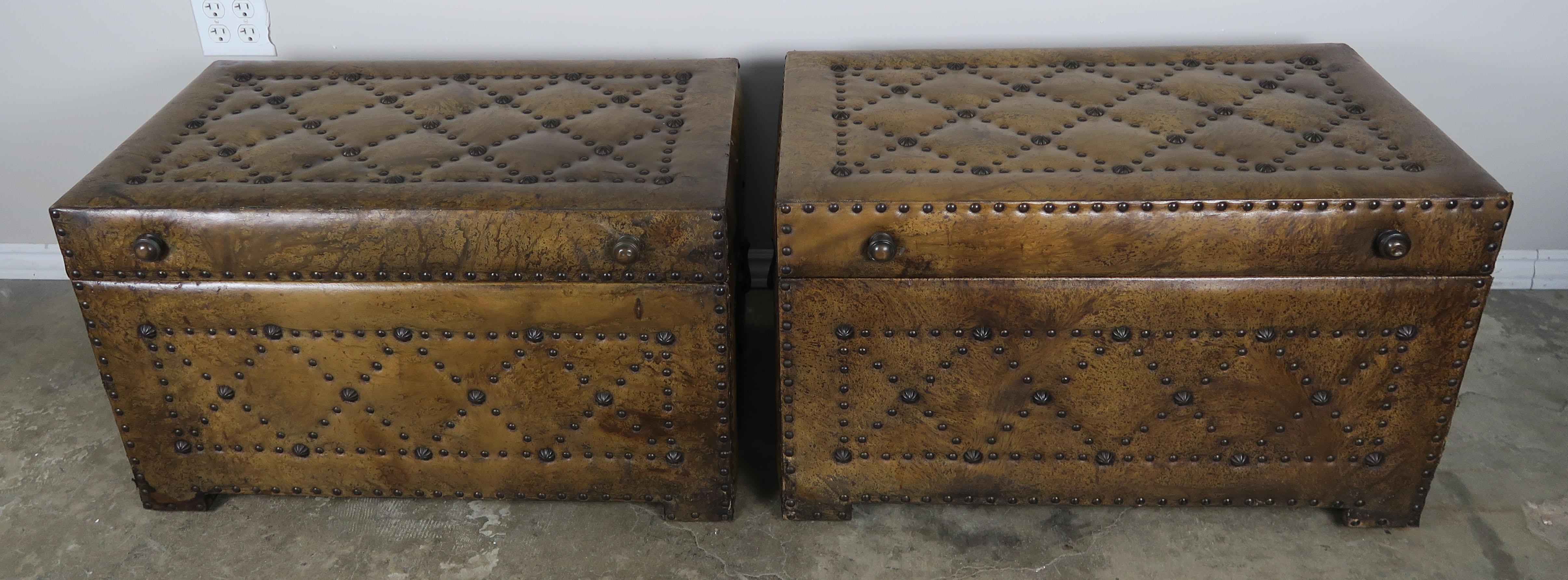 Pair of Spanish tobacco colored leather chests with nailhead trim detail and brass handles. Various antique brass nailheads make up a fabulous criss-cross design throughout both pieces. Great storage pieces for the ends of twin size beds or anywhere